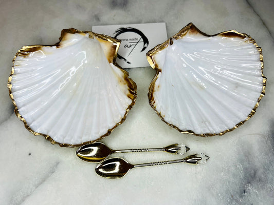 Pair of handmade Dorset scallop shell salt and pepper pinch pots with polished pearl finish, gold leaf edging, and optional gold crystal spoons or serving tongs. Elegant coastal shell cruet set styled for luxury dining and wedding table décor.