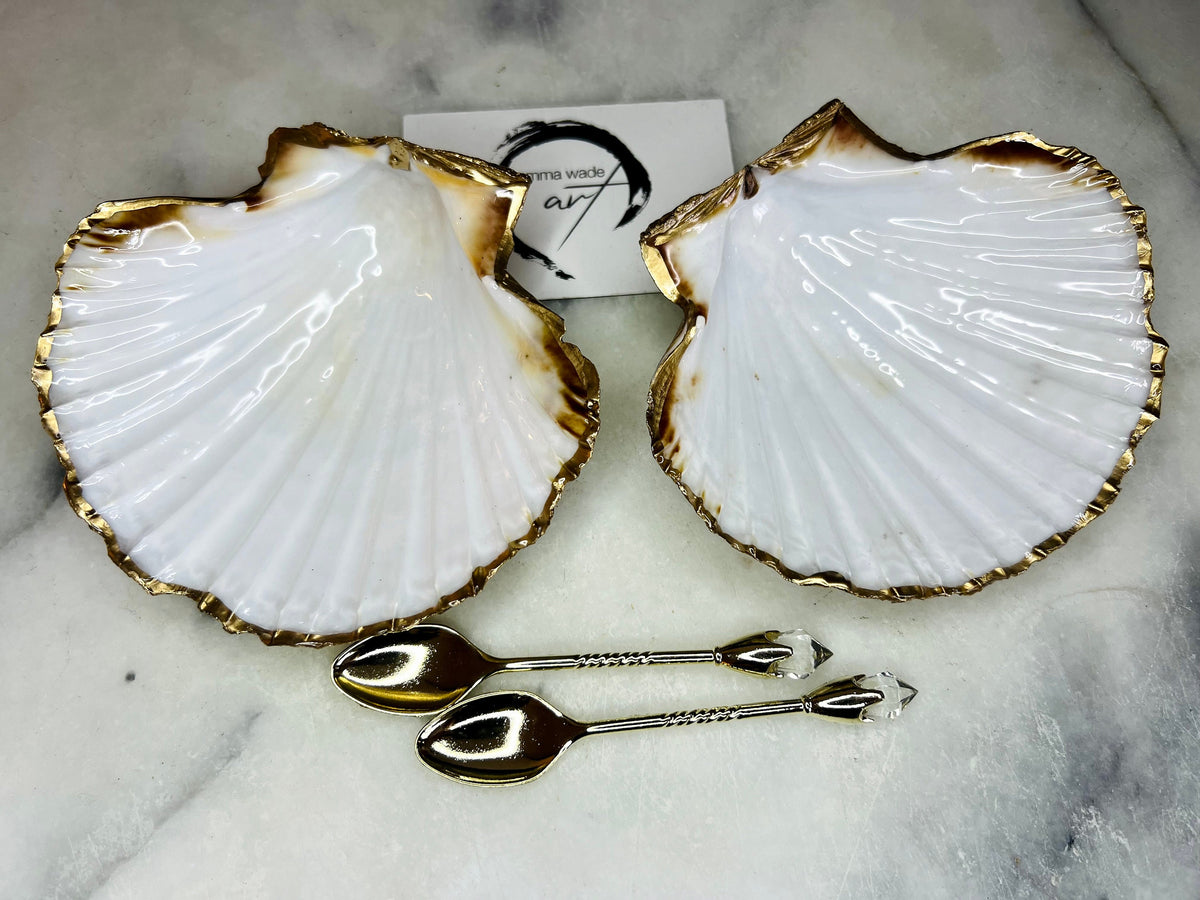 Pair of handmade Dorset scallop shell salt and pepper pinch pots with polished pearl finish, gold leaf edging, and optional gold crystal spoons or serving tongs. Elegant coastal shell cruet set styled for luxury dining and wedding table décor.