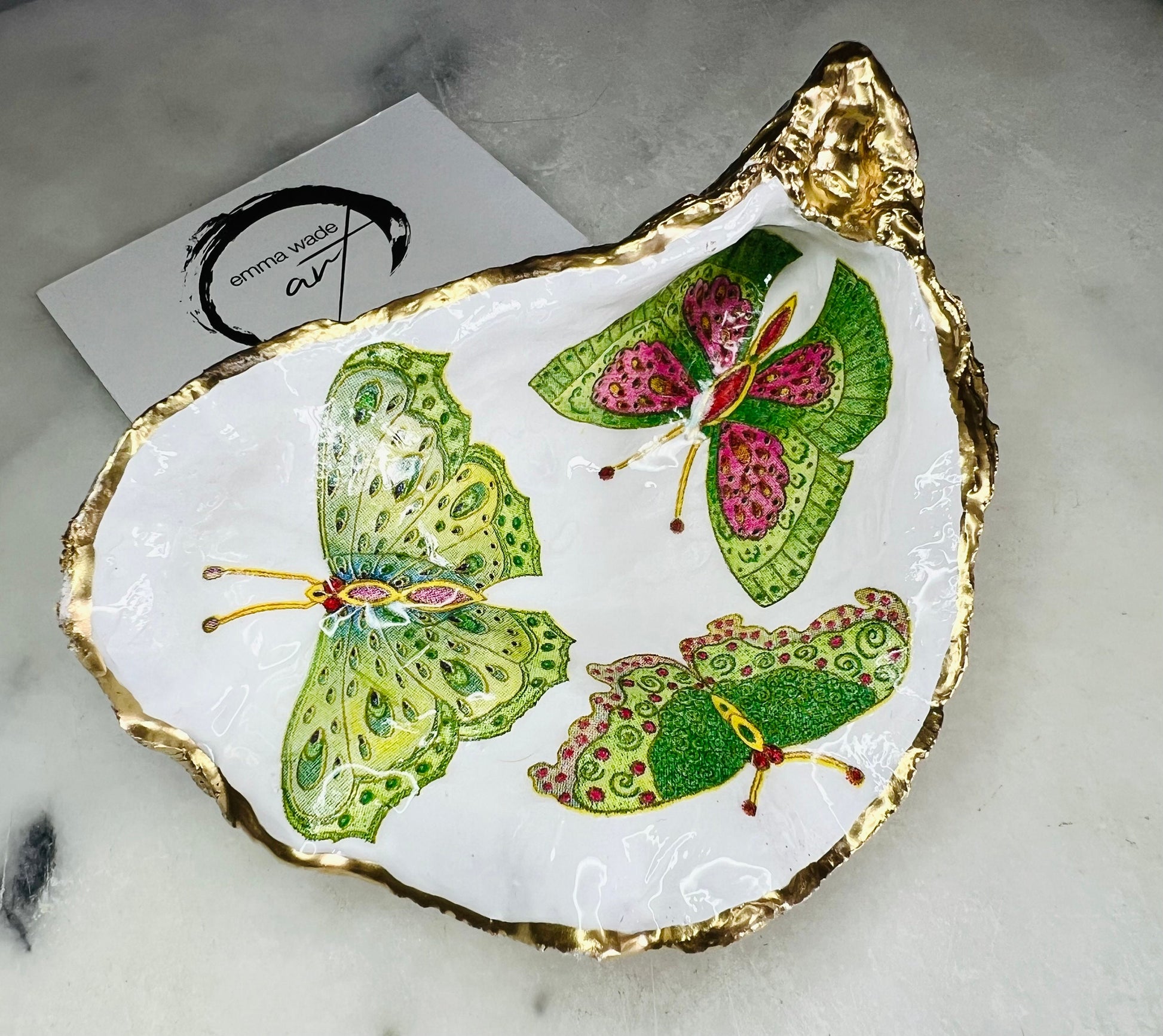 Handmade butterfly oyster shell trinket dish with colourful blue green and pink butterfly designs, edged and backed in gold leaf, Dorset coastal shell jewellery holder with glossy resin finish, luxury ring dish, coastal home decor gift, unique handmade shell dish for jewellery storage, beach house accessory, UK artisan oyster shell dish