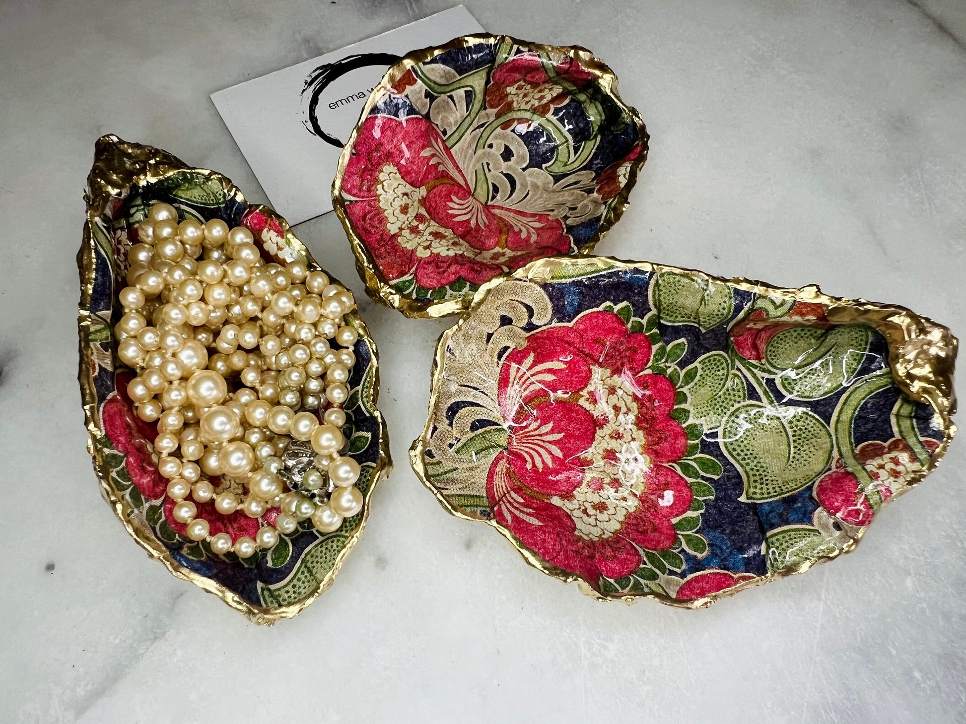 Handmade oyster shell trinket dish featuring a retro floral botanical pattern in pink, red, navy, and olive tones with gold leaf edging and glossy resin finish. Vintage V&A inspired oyster shell jewellery dish styled as coastal cottagecore home décor.