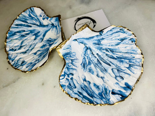 Blue seaweed scallop shell ring catcher with hand applied gold leaf edging and glossy resin finish. Handmade Dorset shell jewellery tray with ocean inspired design styled on marble background. Coastal vanity decor and beach house accessory with optional gold driftwood stand.