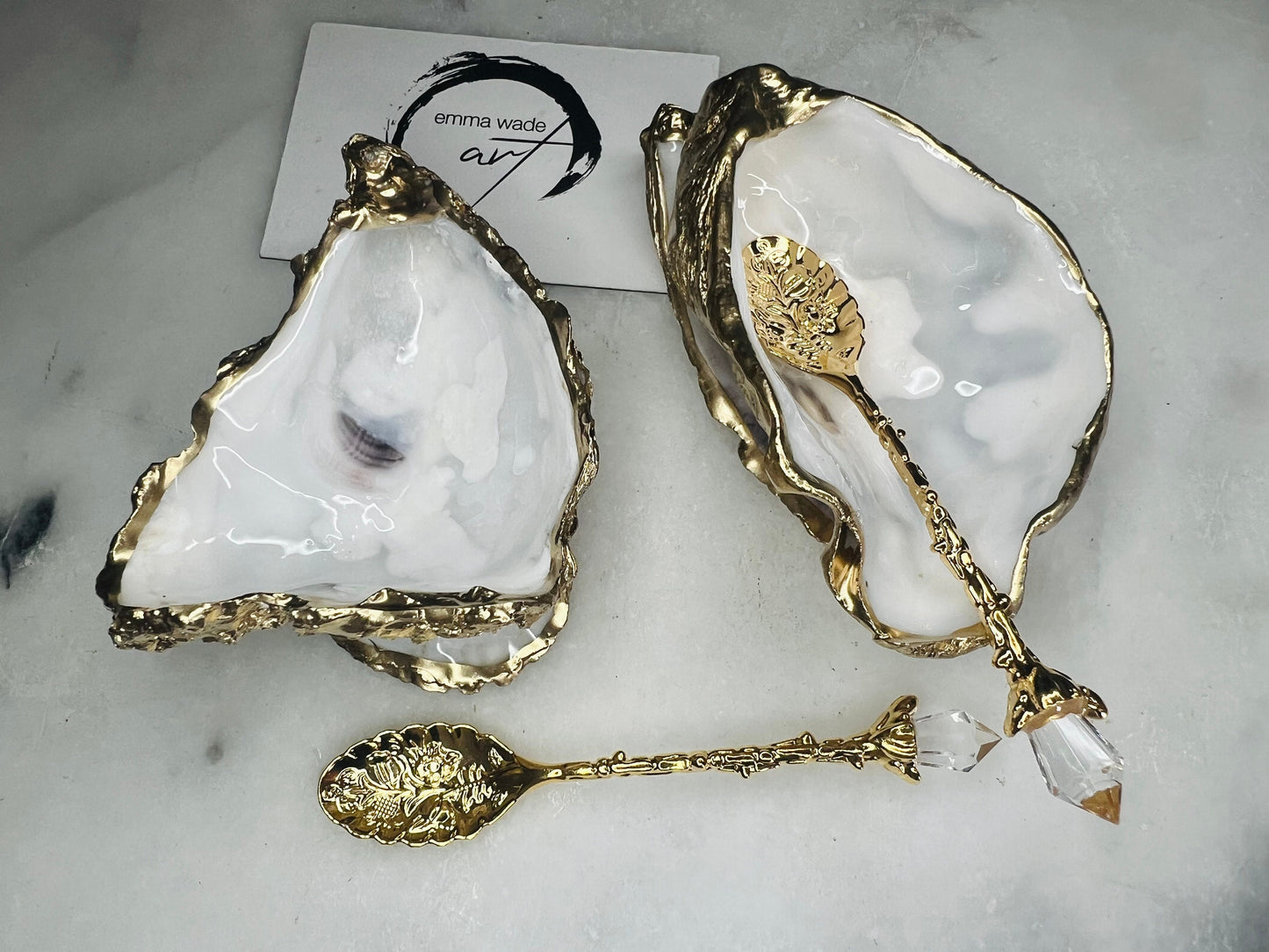 Handcrafted natural Dorset oyster shell salt and pepper pinch pot set with gold leaf edging and matching gold crystal spoons. Coastal luxury table décor featuring pearlescent oyster shells sealed with glossy food-safe resin and presented as elegant artisan cruet dishes.