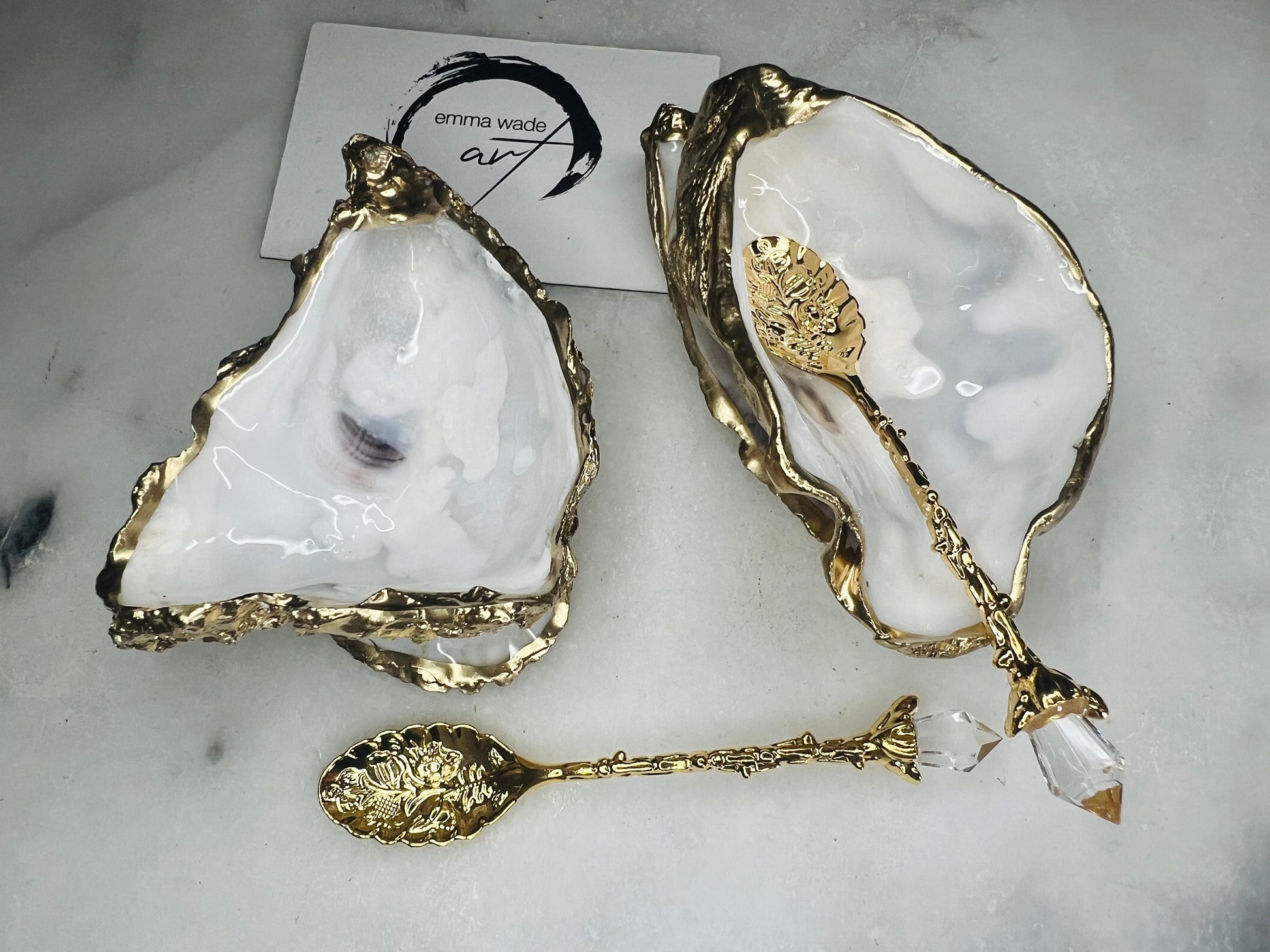 Handcrafted natural Dorset oyster shell salt and pepper pinch pot set with gold leaf edging and matching gold crystal spoons. Coastal luxury table décor featuring pearlescent oyster shells sealed with glossy food-safe resin and presented as elegant artisan cruet dishes.