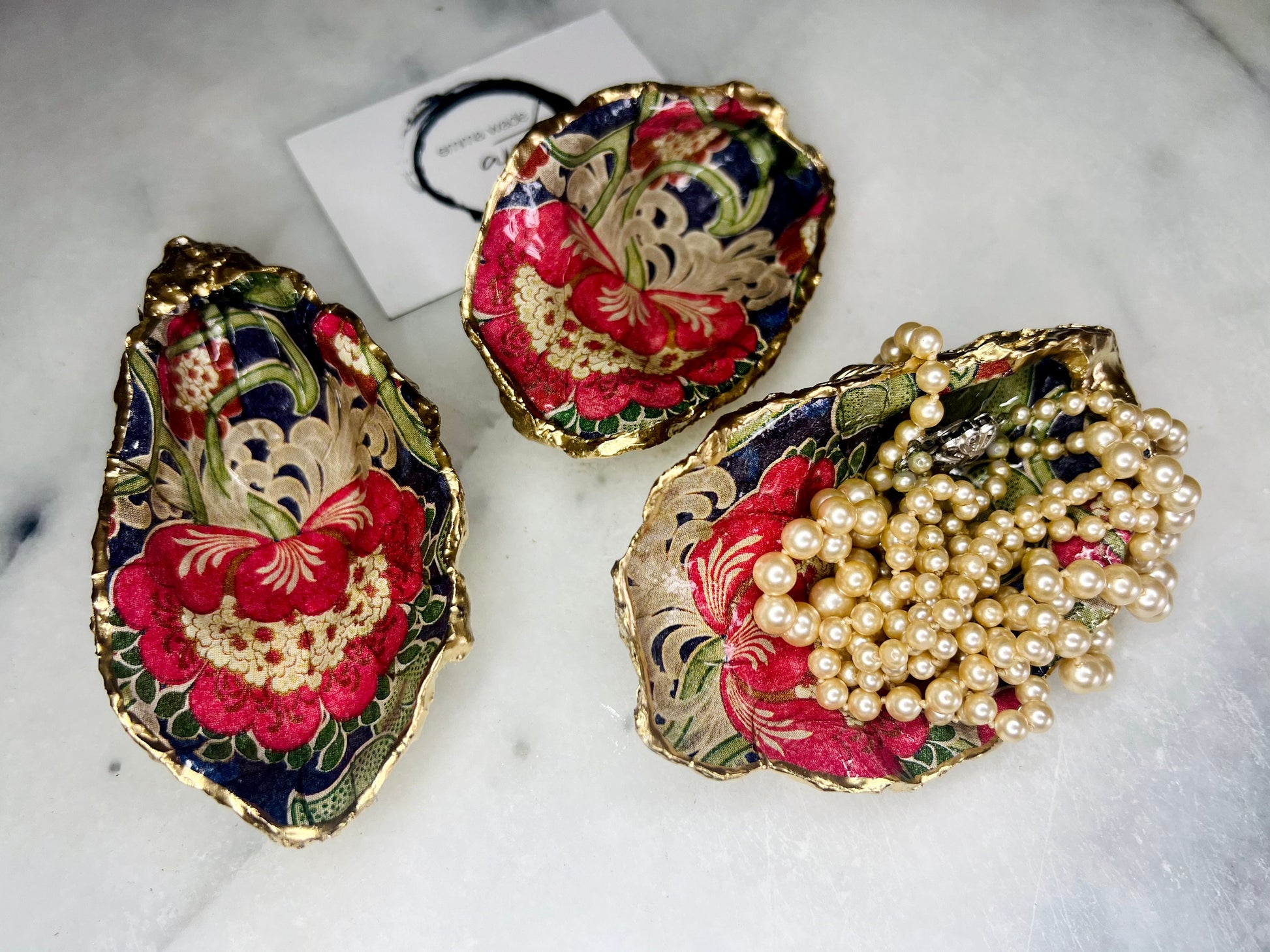 Handmade oyster shell trinket dish featuring a retro floral botanical pattern in pink, red, navy, and olive tones with gold leaf edging and glossy resin finish. Vintage V&A inspired oyster shell jewellery dish styled as coastal cottagecore home décor.
