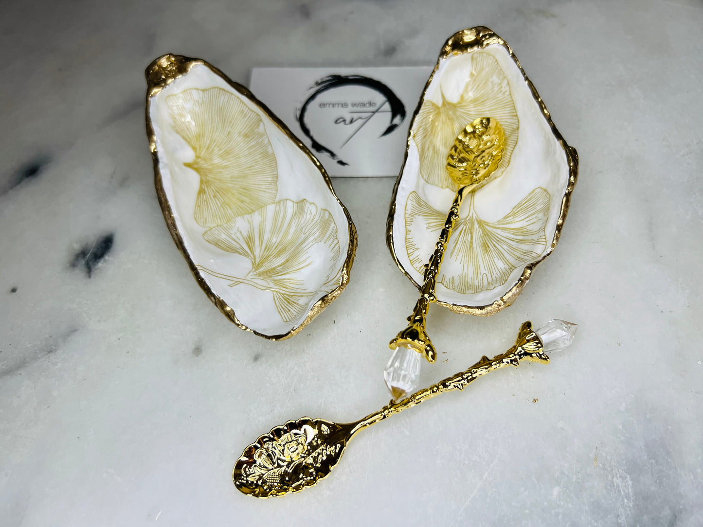 Pair of handmade Dorset oyster shell salt and pepper pinch pots featuring elegant Japanese Ginkgo floral artwork in soft gold and pearl tones with hand-applied gold leaf edging. Coastal luxury cruet set sealed in glossy Crystal resin with optional gold crystal spoons.