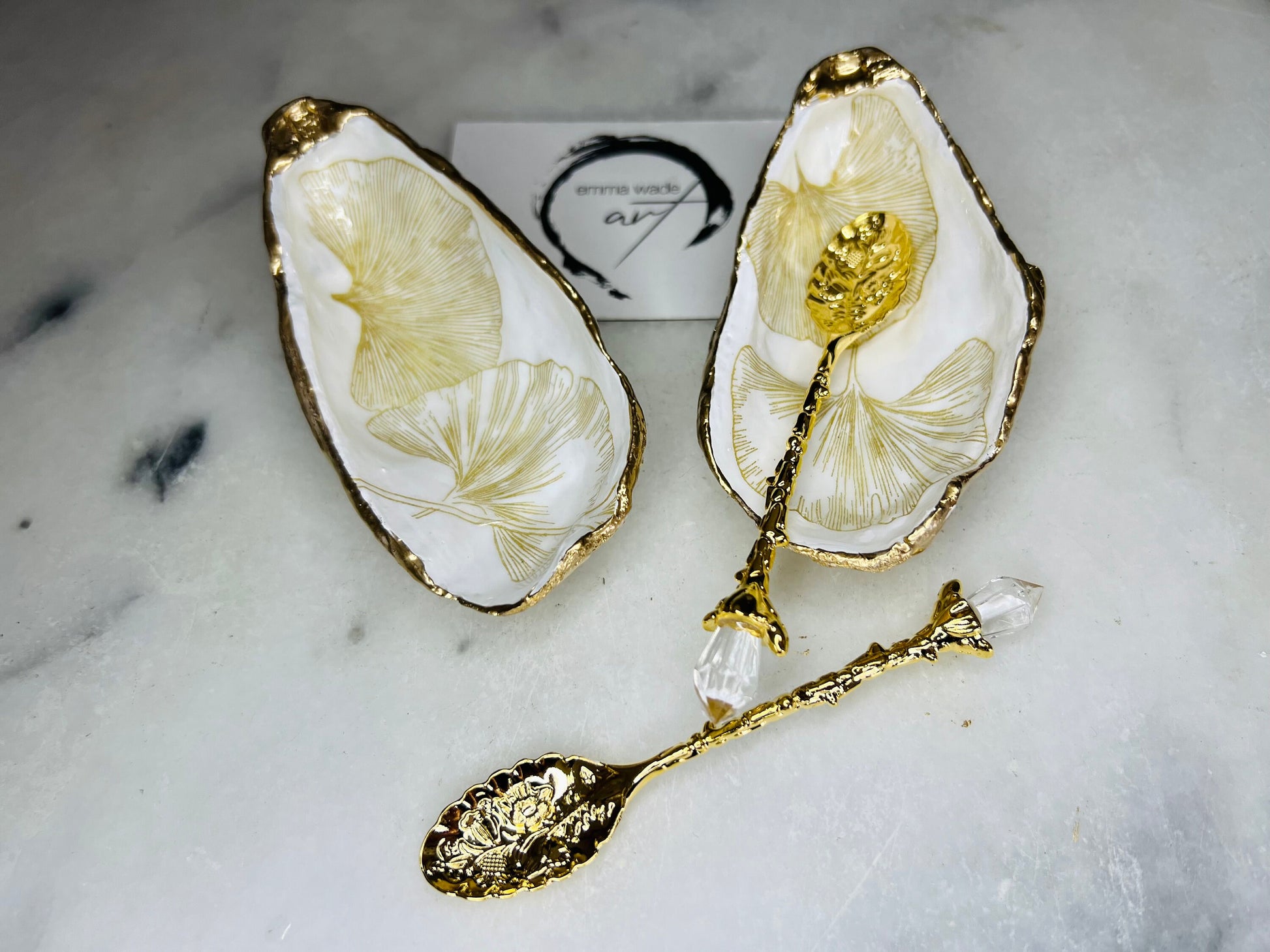 Pair of handmade Dorset oyster shell salt and pepper pinch pots featuring elegant Japanese Ginkgo floral artwork in soft gold and pearl tones with hand-applied gold leaf edging. Coastal luxury cruet set sealed in glossy Crystal resin with optional gold crystal spoons.