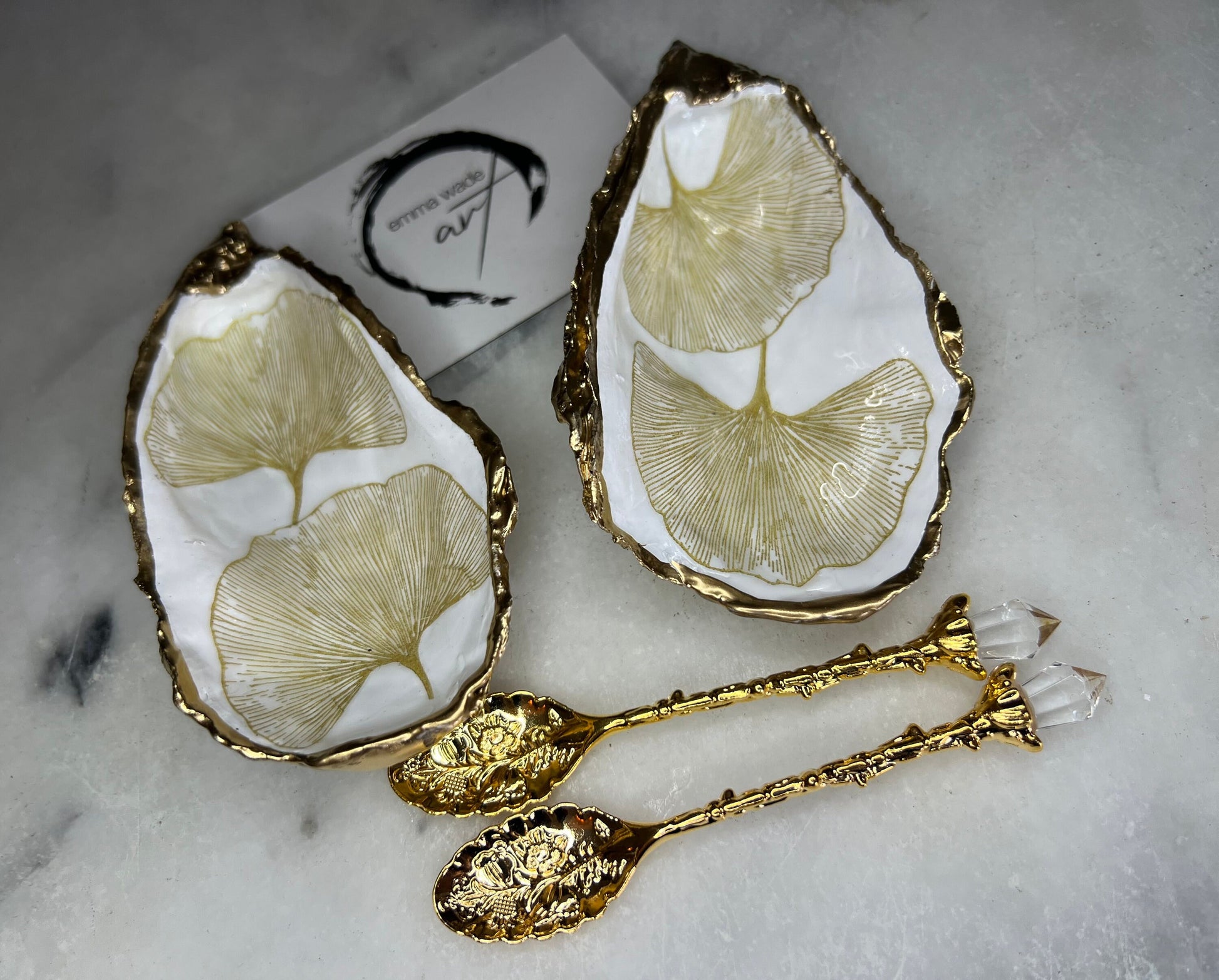 Pair of handmade Dorset oyster shell salt and pepper pinch pots featuring elegant Japanese Ginkgo floral artwork in soft gold and pearl tones with hand-applied gold leaf edging. Coastal luxury cruet set sealed in glossy Crystal resin with optional gold crystal spoons.