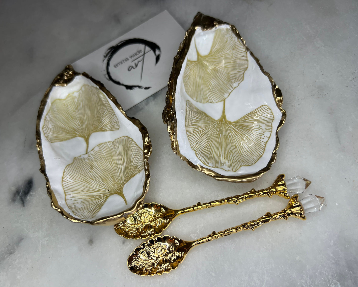 Pair of handmade Dorset oyster shell salt and pepper pinch pots featuring elegant Japanese Ginkgo floral artwork in soft gold and pearl tones with hand-applied gold leaf edging. Coastal luxury cruet set sealed in glossy Crystal resin with optional gold crystal spoons.