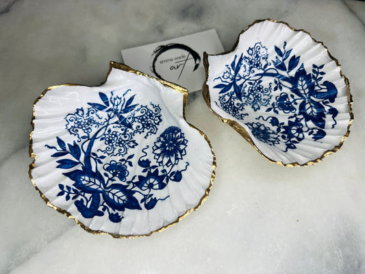 Handmade blue onion floral scallop shell trinket dish with gold leaf edging, shown on a light background. Crafted from a natural Dorset scallop shell, the dish features a classic blue and white floral pattern inspired by traditional onion designs, sealed with glossy epoxy resin. Designed as a jewellery or ring holder, this decorative shell dish is finished by hand and each piece is unique.
