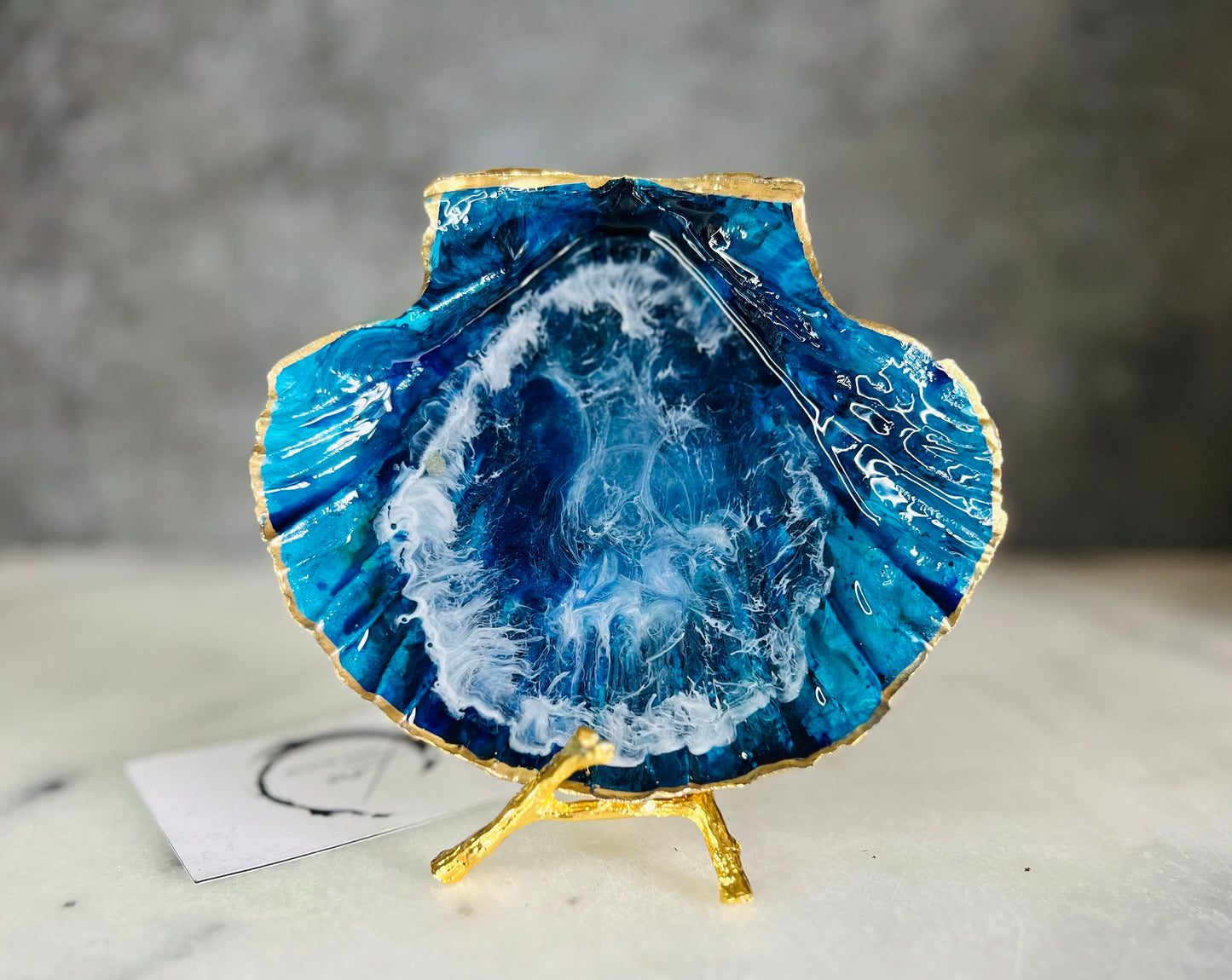 Extra large hand painted Dorset scallop shell dish inspired by ocean caves and sea grottos, featuring layered blue acrylic inks and crystal clear resin art with foaming wave details, hand gilded with liquid gold leaf on the rim and reverse, luxury coastal trinket dish, ocean inspired jewellery holder, handmade resin shell decor UK