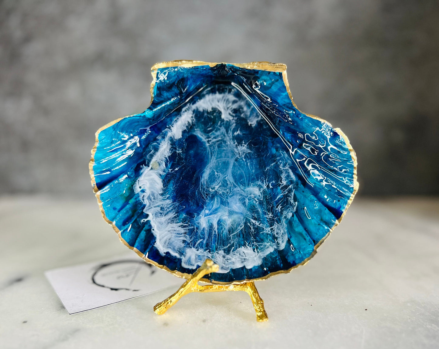 Extra large hand painted Dorset scallop shell dish inspired by ocean caves and sea grottos, featuring layered blue acrylic inks and crystal clear resin art with foaming wave details, hand gilded with liquid gold leaf on the rim and reverse, luxury coastal trinket dish, ocean inspired jewellery holder, handmade resin shell decor UK