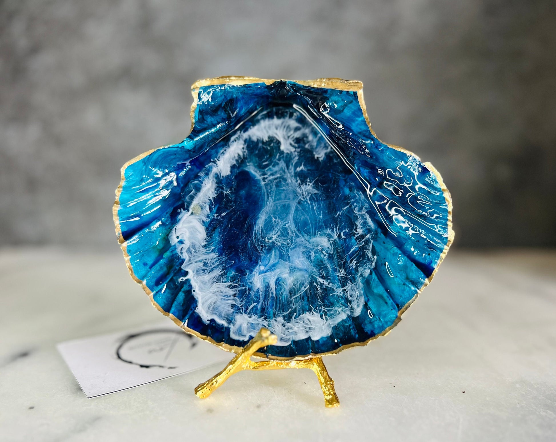 Extra large hand painted Dorset scallop shell dish inspired by ocean caves and sea grottos, featuring layered blue acrylic inks and crystal clear resin art with foaming wave details, hand gilded with liquid gold leaf on the rim and reverse, luxury coastal trinket dish, ocean inspired jewellery holder, handmade resin shell decor UK