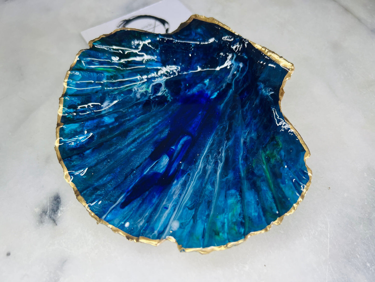 Extra large hand-painted Dorset scallop shell trinket dish featuring deep blue ocean-inspired resin artwork with turquoise wave details, hand gilded gold edging, glossy coastal jewellery holder and luxury seaside décor