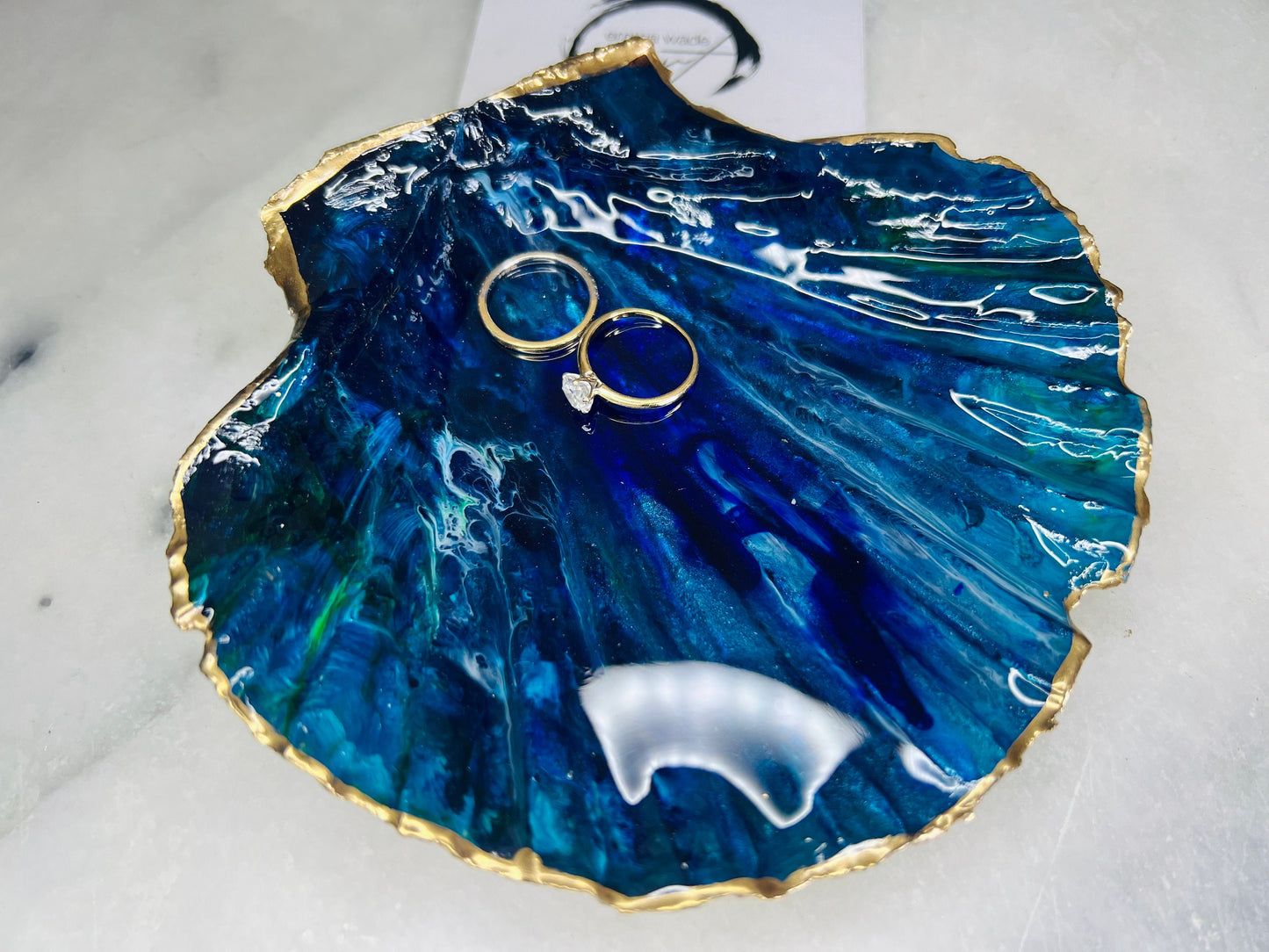 Extra large hand-painted Dorset scallop shell trinket dish featuring deep blue ocean-inspired resin artwork with turquoise wave details, hand gilded gold edging, glossy coastal jewellery holder and luxury seaside décor