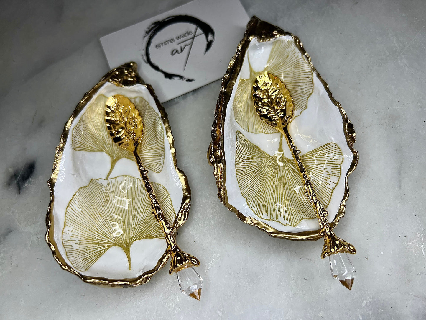 Pair of handmade Dorset oyster shell salt and pepper pinch pots featuring elegant Japanese Ginkgo floral artwork in soft gold and pearl tones with hand-applied gold leaf edging. Coastal luxury cruet set sealed in glossy Crystal resin with optional gold crystal spoons.