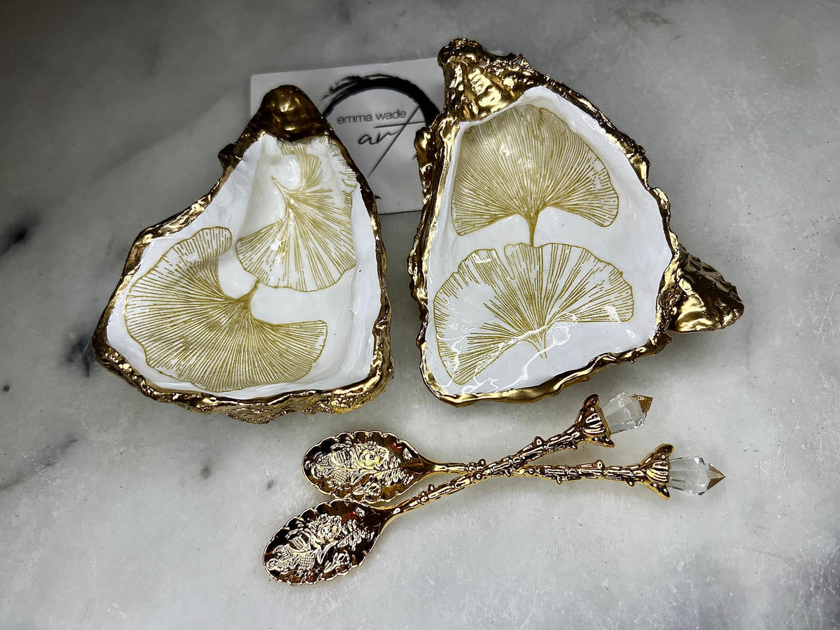 Pair of handmade Dorset oyster shell salt and pepper pinch pots featuring elegant Japanese Ginkgo floral artwork in soft gold and pearl tones with hand-applied gold leaf edging. Coastal luxury cruet set sealed in glossy Crystal resin with optional gold crystal spoons.