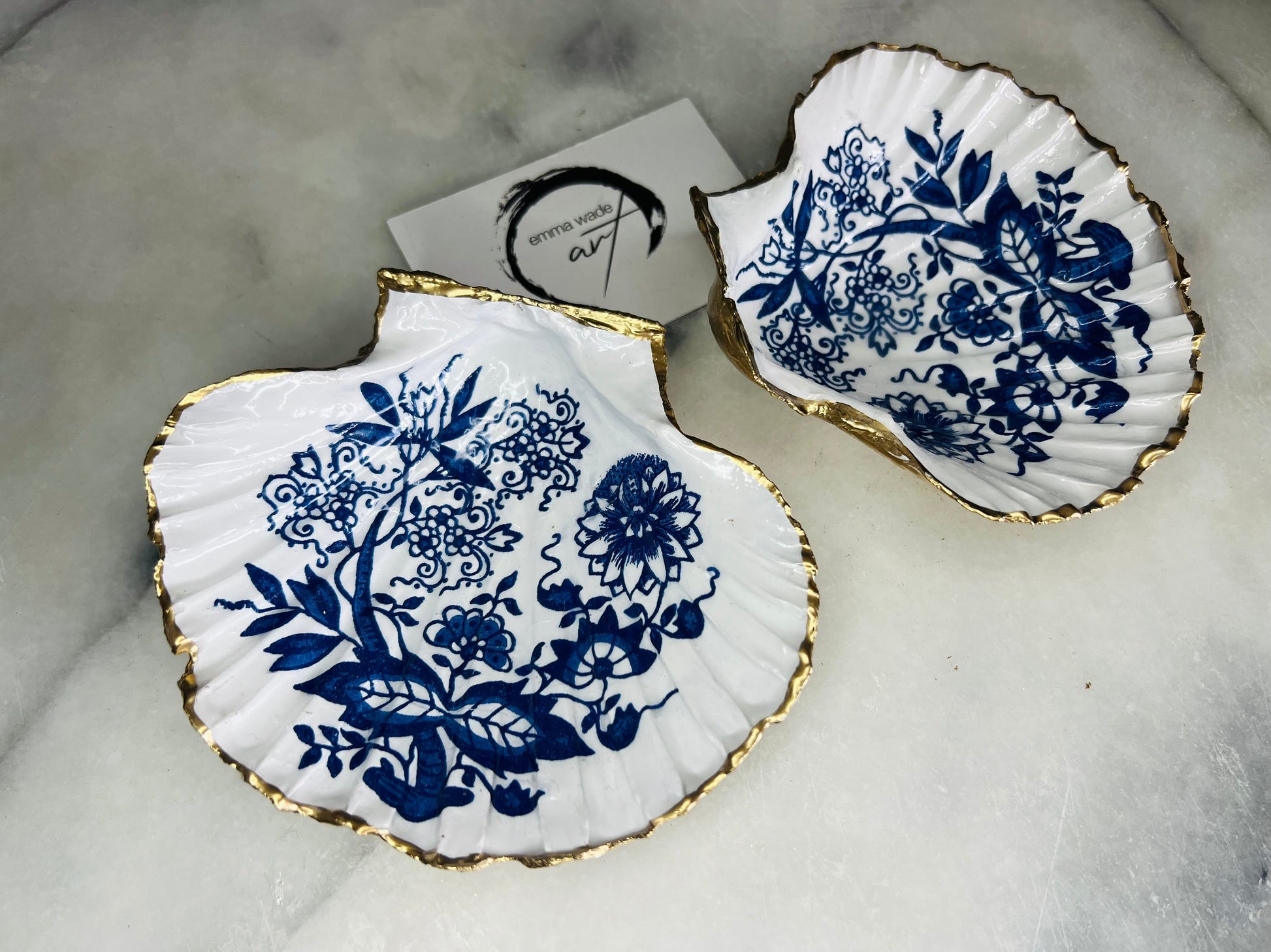 Handmade blue onion floral scallop shell trinket dish with gold leaf edging, shown on a light background. Crafted from a natural Dorset scallop shell, the dish features a classic blue and white floral pattern inspired by traditional onion designs, sealed with glossy epoxy resin. Designed as a jewellery or ring holder, this decorative shell dish is finished by hand and each piece is unique.
