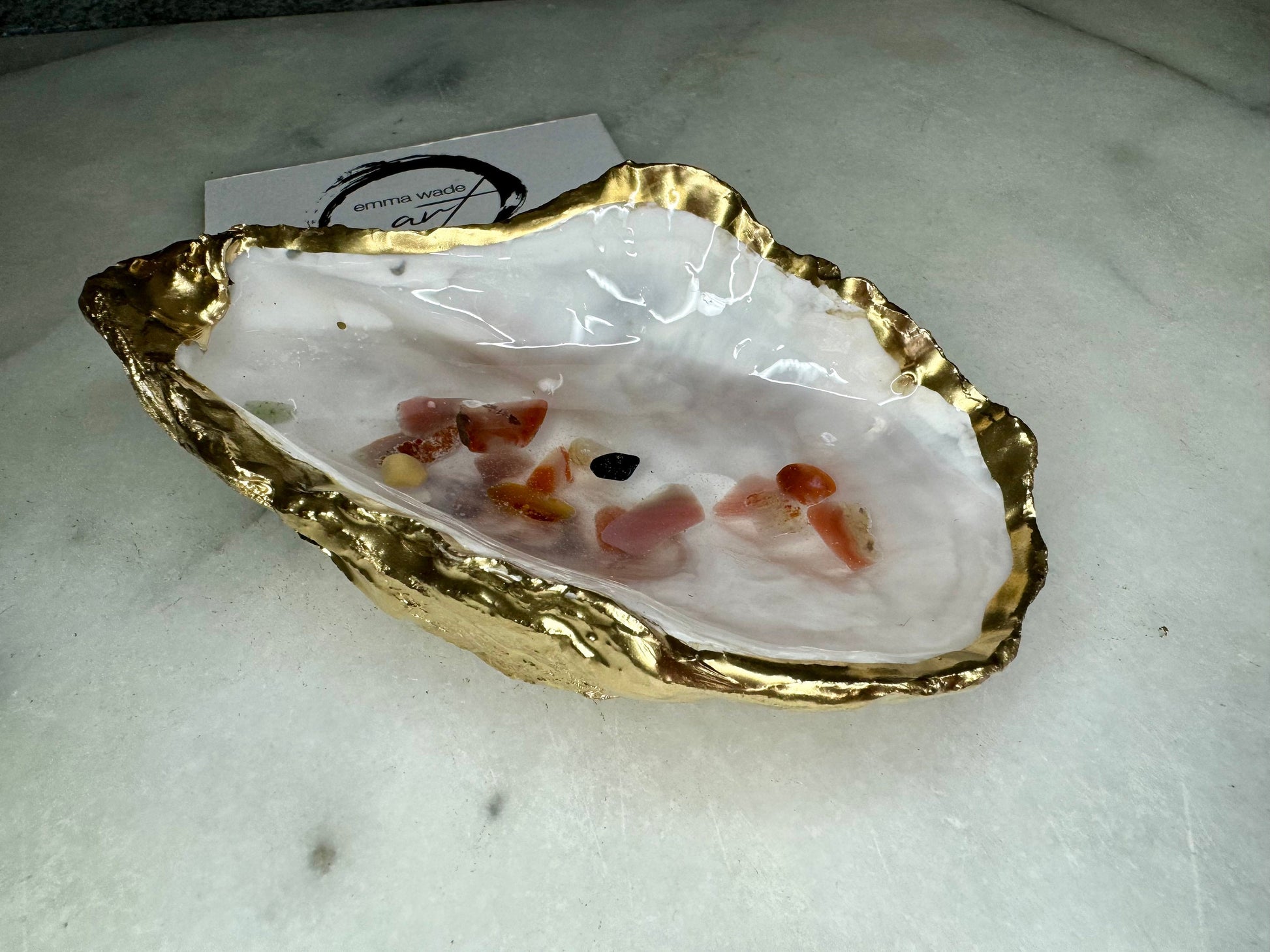 Handmade oyster shell jewellery dish with real Dorset sea glass foraged from the coast and suspended in clear glossy resin to look like a rock pool. Finished with gold leaf trim and a natural pearl interior, this unique shell dish can be used as a ring holder, jewellery tray, or trinket catcher for earrings, cufflinks, or keepsakes. A one-of-a-kind coastal-inspired gift for weddings, anniversaries, birthdays, bridesmaids, Christmas, or Mother’s Day.