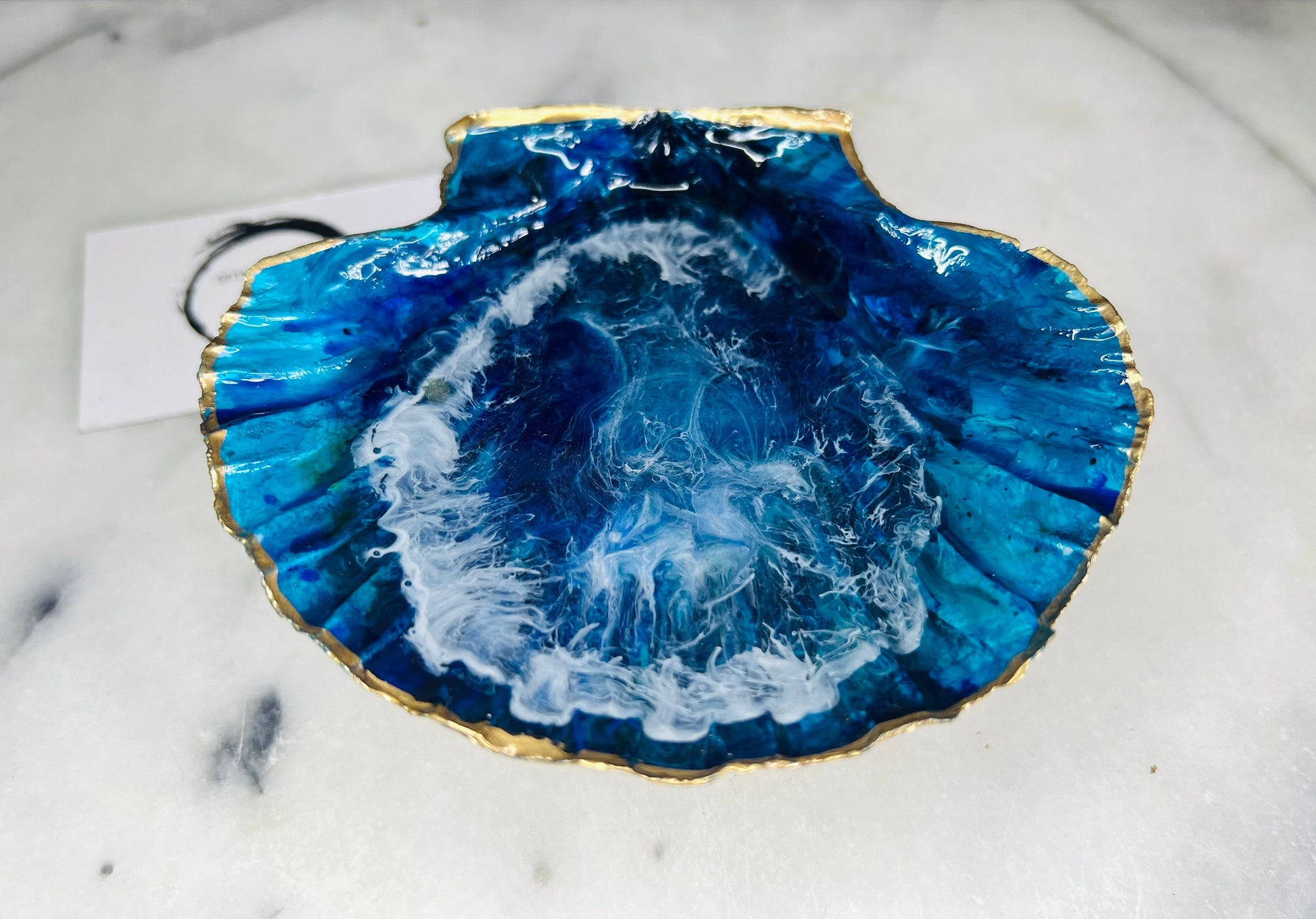 Extra large hand painted Dorset scallop shell dish inspired by ocean caves and sea grottos, featuring layered blue acrylic inks and crystal clear resin art with foaming wave details, hand gilded with liquid gold leaf on the rim and reverse, luxury coastal trinket dish, ocean inspired jewellery holder, handmade resin shell decor UK
