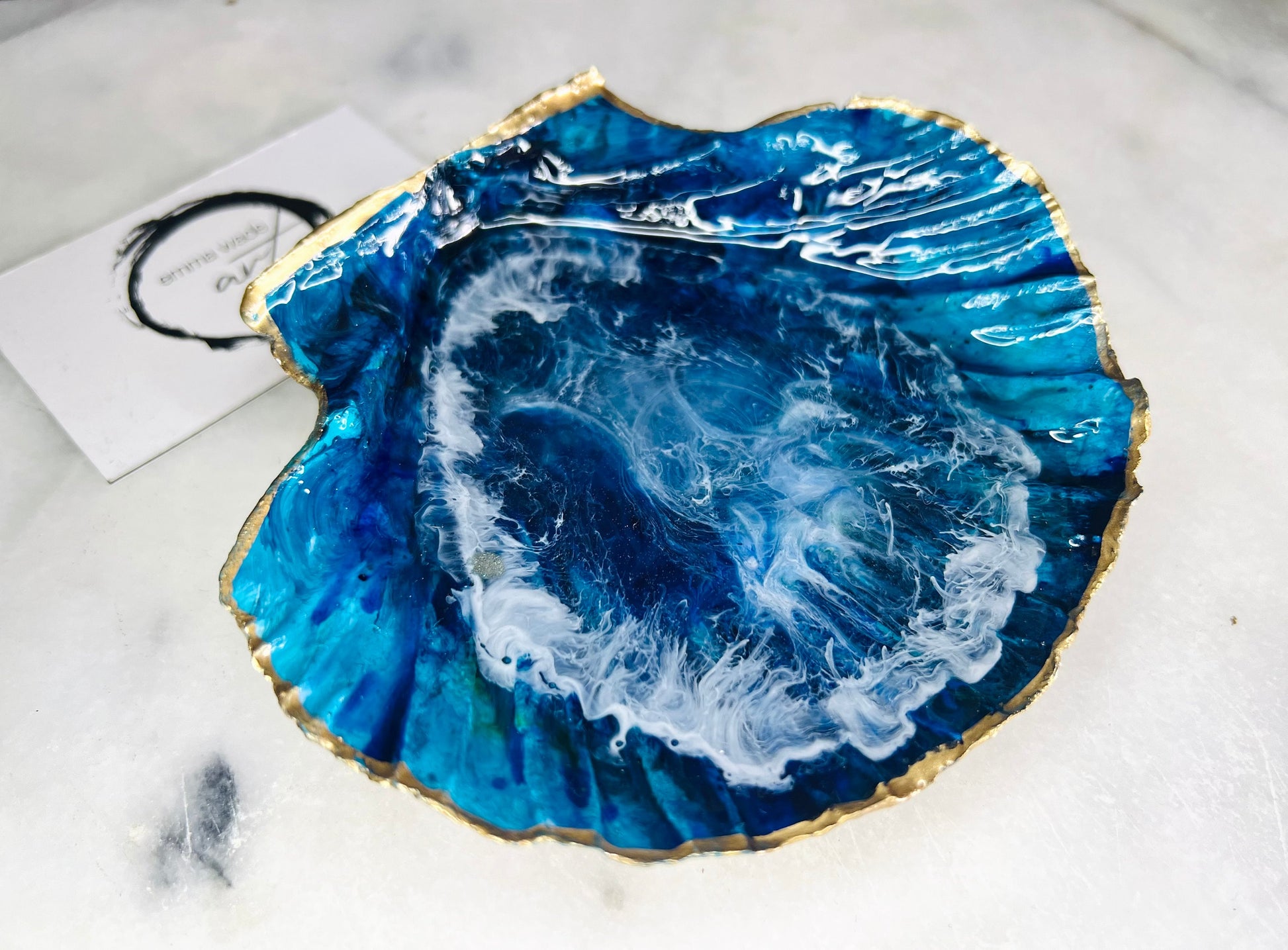 Extra large hand painted Dorset scallop shell dish inspired by ocean caves and sea grottos, featuring layered blue acrylic inks and crystal clear resin art with foaming wave details, hand gilded with liquid gold leaf on the rim and reverse, luxury coastal trinket dish, ocean inspired jewellery holder, handmade resin shell decor UK