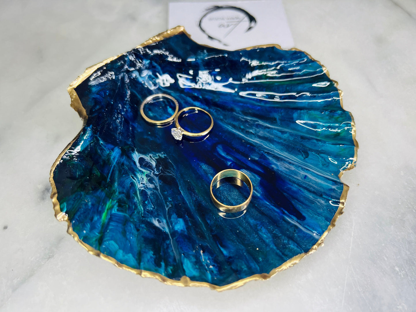Extra large hand-painted Dorset scallop shell trinket dish featuring deep blue ocean-inspired resin artwork with turquoise wave details, hand gilded gold edging, glossy coastal jewellery holder and luxury seaside décor