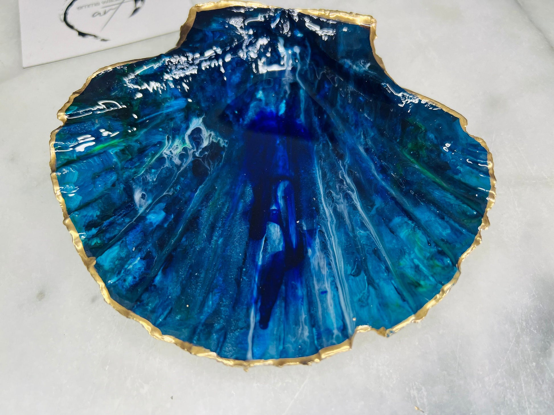 Extra large hand-painted Dorset scallop shell trinket dish featuring deep blue ocean-inspired resin artwork with turquoise wave details, hand gilded gold edging, glossy coastal jewellery holder and luxury seaside décor