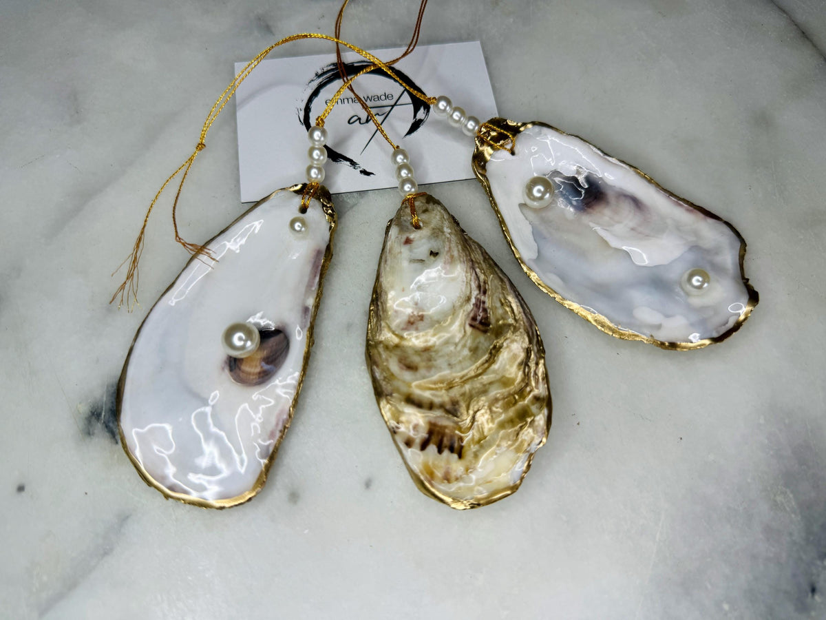 Luxury flat pearl oyster shell hanging ornaments handcrafted from natural Dorset oyster shells with glossy pearlescent interiors, two Swarovski pearls per ornament and hand-painted gold leaf edging. Elegant coastal hanging decor finished in crystal clear resin with gold hanging cord and pearl bead details. Available individually or as a set of three. Perfect for beach house interiors, luxury bathroom styling, wedding gifts, coastal Christmas decor and year-round shell home decor.