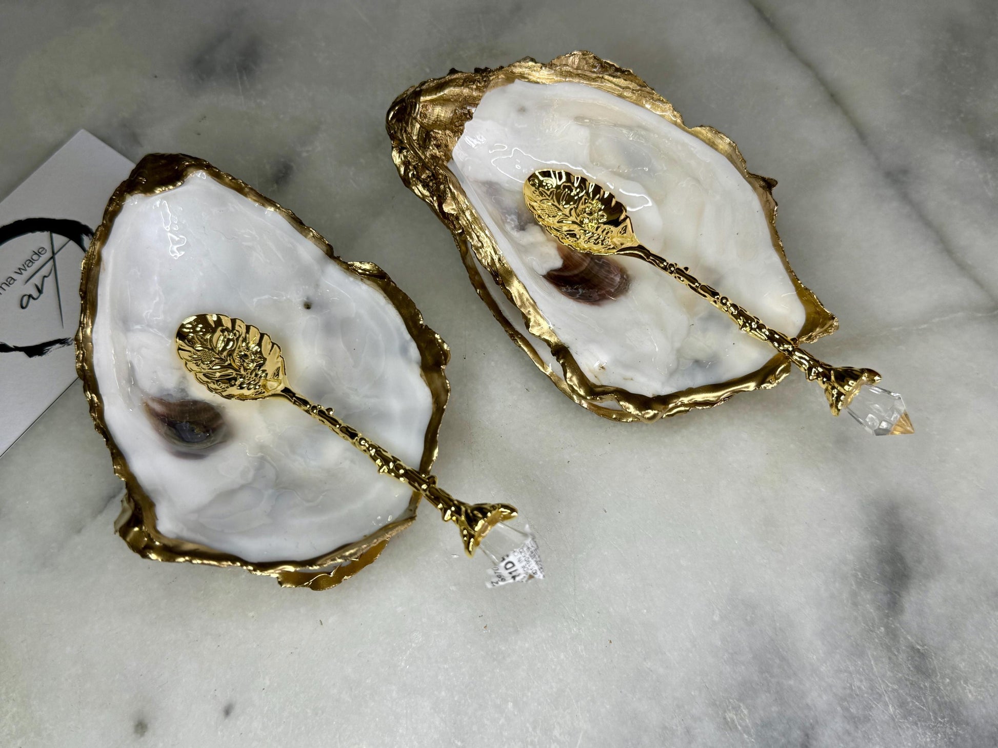 Handcrafted natural Dorset oyster shell salt and pepper pinch pot set with gold leaf edging and matching gold crystal spoons. Coastal luxury table décor featuring pearlescent oyster shells sealed with glossy food-safe resin and presented as elegant artisan cruet dishes.