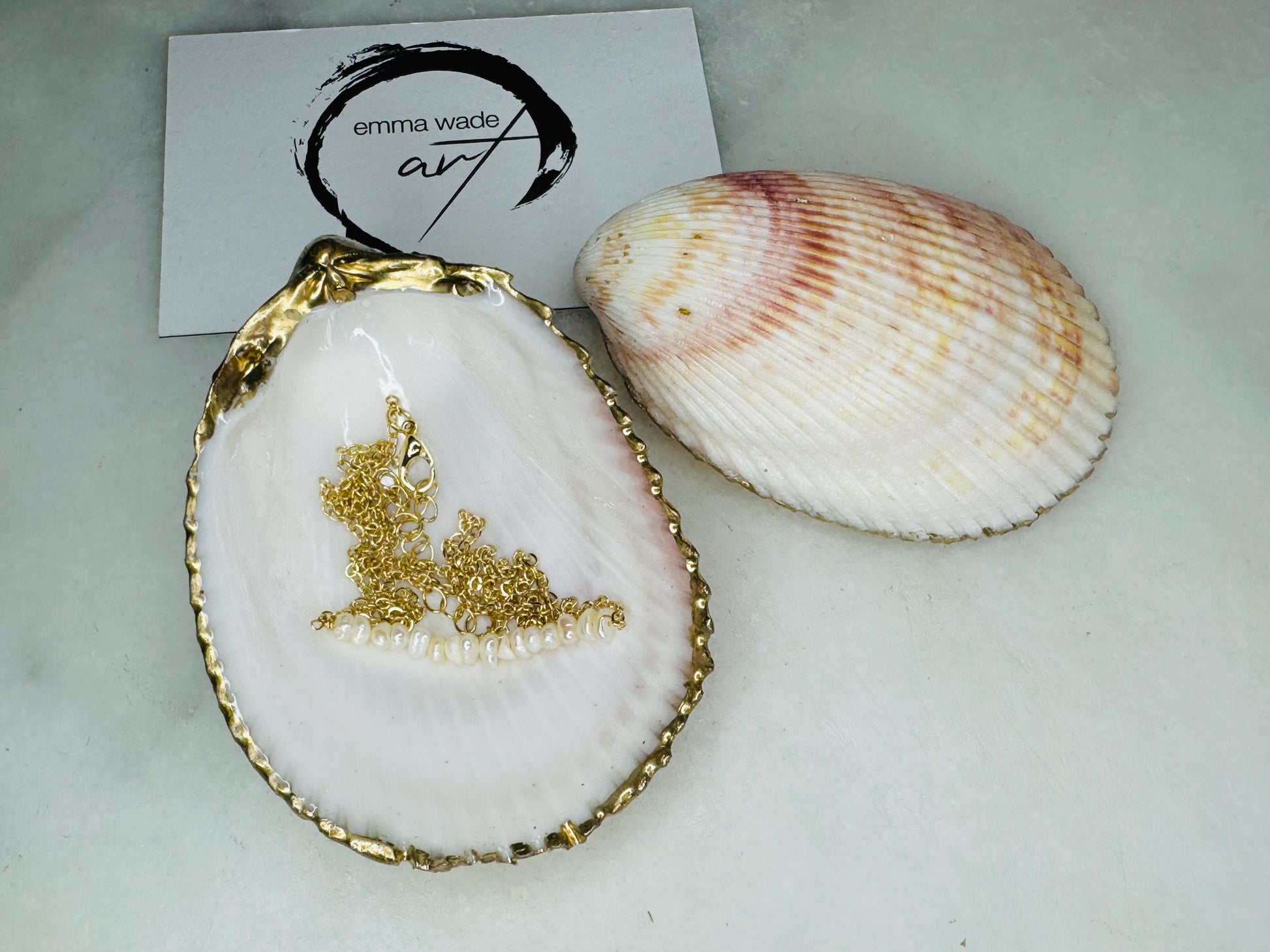 Handmade gold gilded cockle shell jewellery box with pearly white interior and optional freshwater pearl necklace. Coastal shell ring box crafted from natural Dorset shells, edged with liquid gold leaf and presented in a luxury gift box. Elegant seaside-inspired keepsake gift for weddings, bridesmaids, birthdays, anniversaries, or jewellery storage.