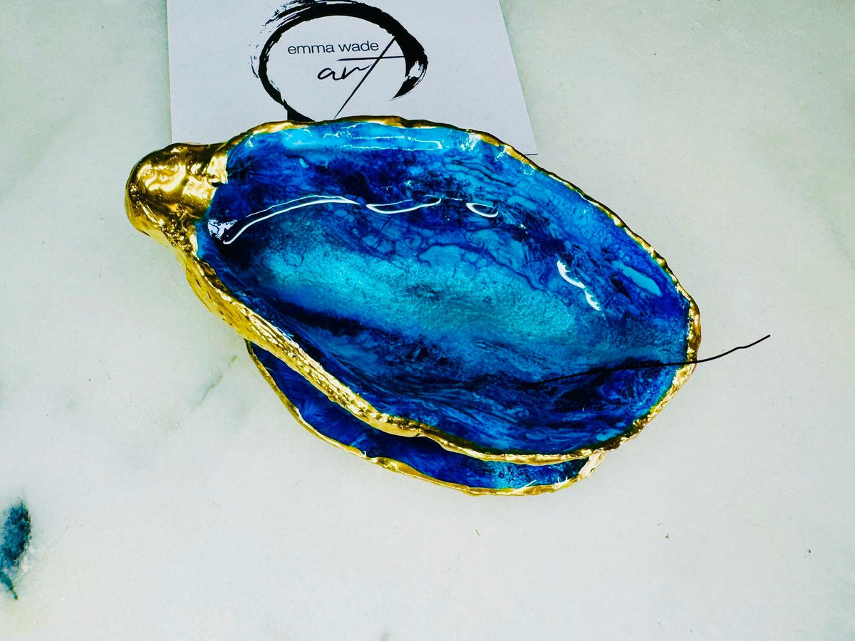 Blue oyster shell ring box, hand painted to resemble ocean waves in rich blue tones with metallic detail and finished with gold leaf edges. Includes a matching painted lid. Each shell is approx. 10cm and crafted from Dorset coastlines, making every piece unique. A stunning ocean-inspired jewellery box, ring bearer box, or proposal ring holder. Perfect for weddings, engagements, anniversaries, or as a keepsake gift for someone special who loves the sea.