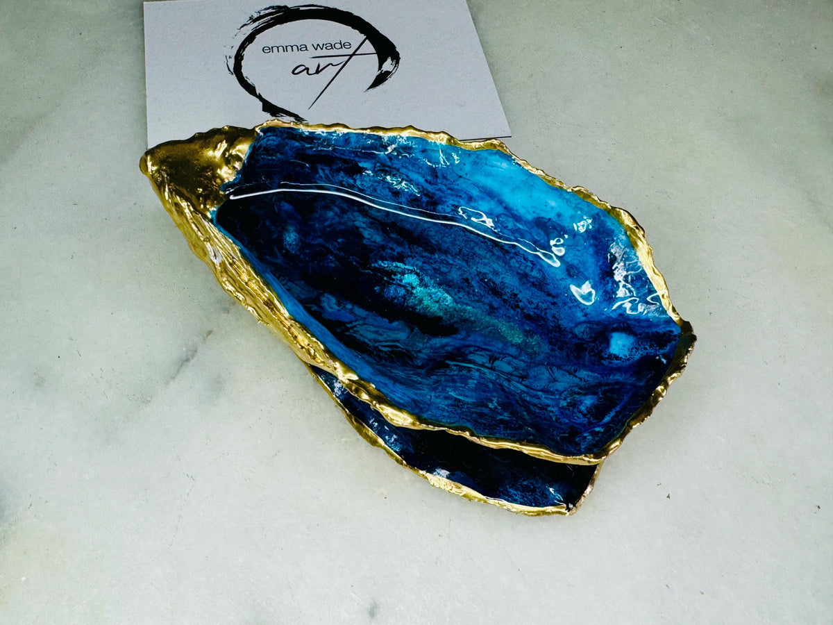 Blue oyster shell ring box, hand painted to resemble ocean waves in rich blue tones with metallic detail and finished with gold leaf edges. Includes a matching painted lid. Each shell is approx. 10cm and crafted from Dorset coastlines, making every piece unique. A stunning ocean-inspired jewellery box, ring bearer box, or proposal ring holder. Perfect for weddings, engagements, anniversaries, or as a keepsake gift for someone special who loves the sea.
