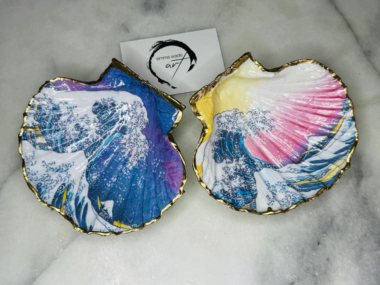 Handcrafted Great Wave of Kanagawa scallop shell trinket dish inspired by Hokusai’s iconic Japanese woodblock print. Each Dorset shell is hand-drawn, painted, and sealed in resin, with a choice of Dawn or Dusk design. Finished with a natural varnished back and gold rim or fully gilded in liquid gold leaf. A unique handmade jewellery holder or coastal art gift, beautifully presented in sustainable packaging.