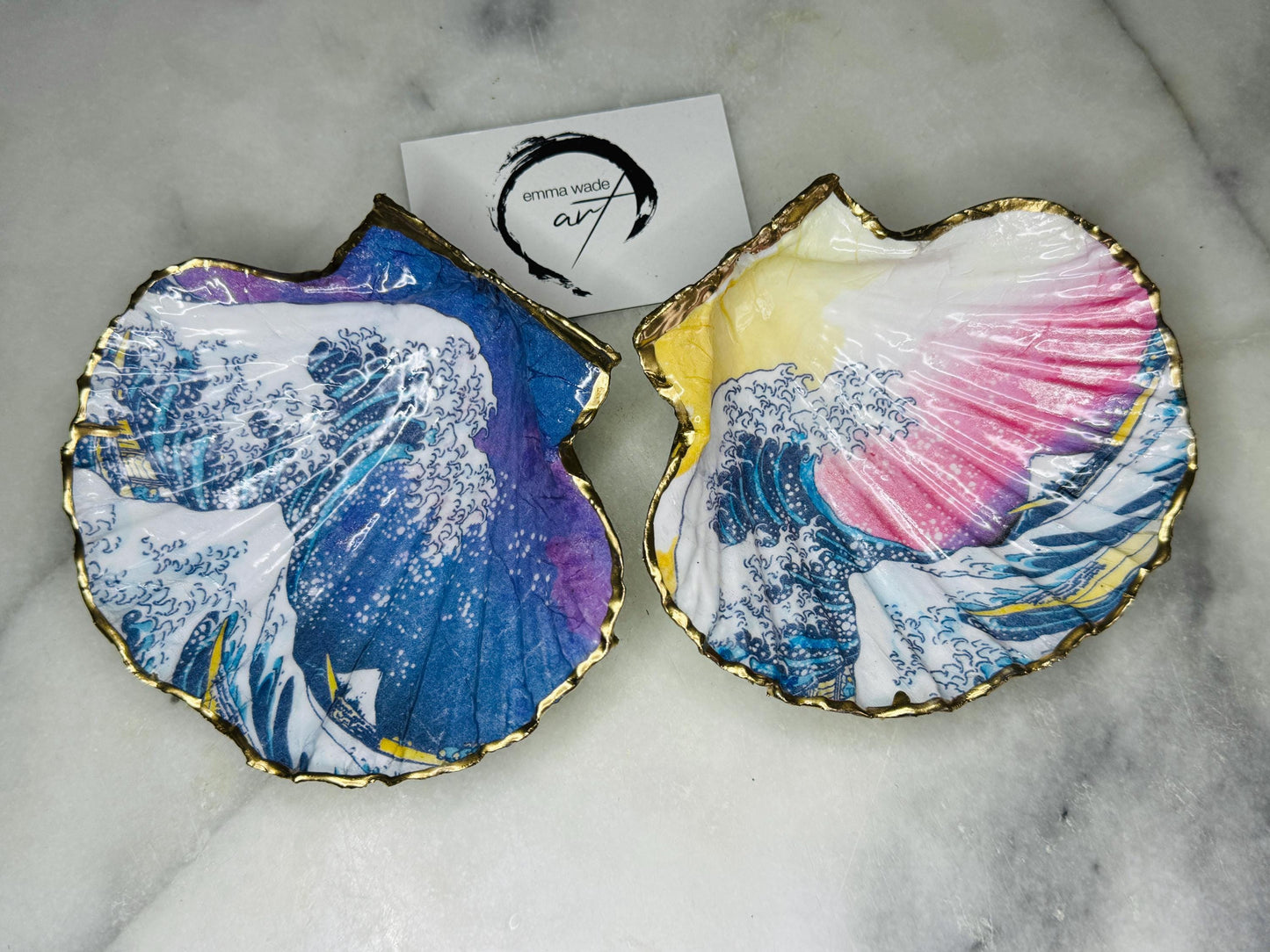Handcrafted Great Wave of Kanagawa scallop shell trinket dish inspired by Hokusai’s iconic Japanese woodblock print. Each Dorset shell is hand-drawn, painted, and sealed in resin, with a choice of Dawn or Dusk design. Finished with a natural varnished back and gold rim or fully gilded in liquid gold leaf. A unique handmade jewellery holder or coastal art gift, beautifully presented in sustainable packaging.