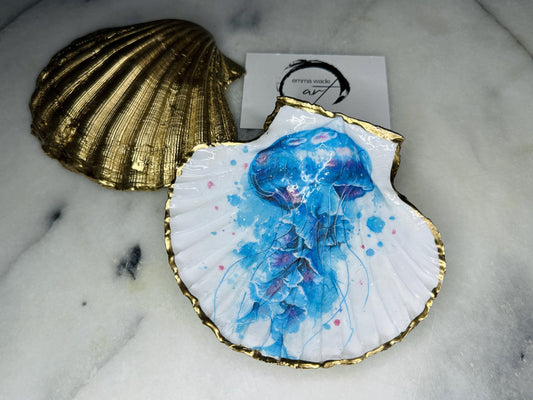 Hand illustrated blue jellyfish scallop shell trinket dish featuring original Emma Wade ART watercolour artwork. Natural Dorset scallop shell finished with hand-gilded gold leaf edging and crystal-clear resin gloss. Coastal jewellery dish, ring holder, trinket tray and ocean-inspired home decor gift. Blue and pink jellyfish design with luxury gold finish, handmade in Surrey, UK.