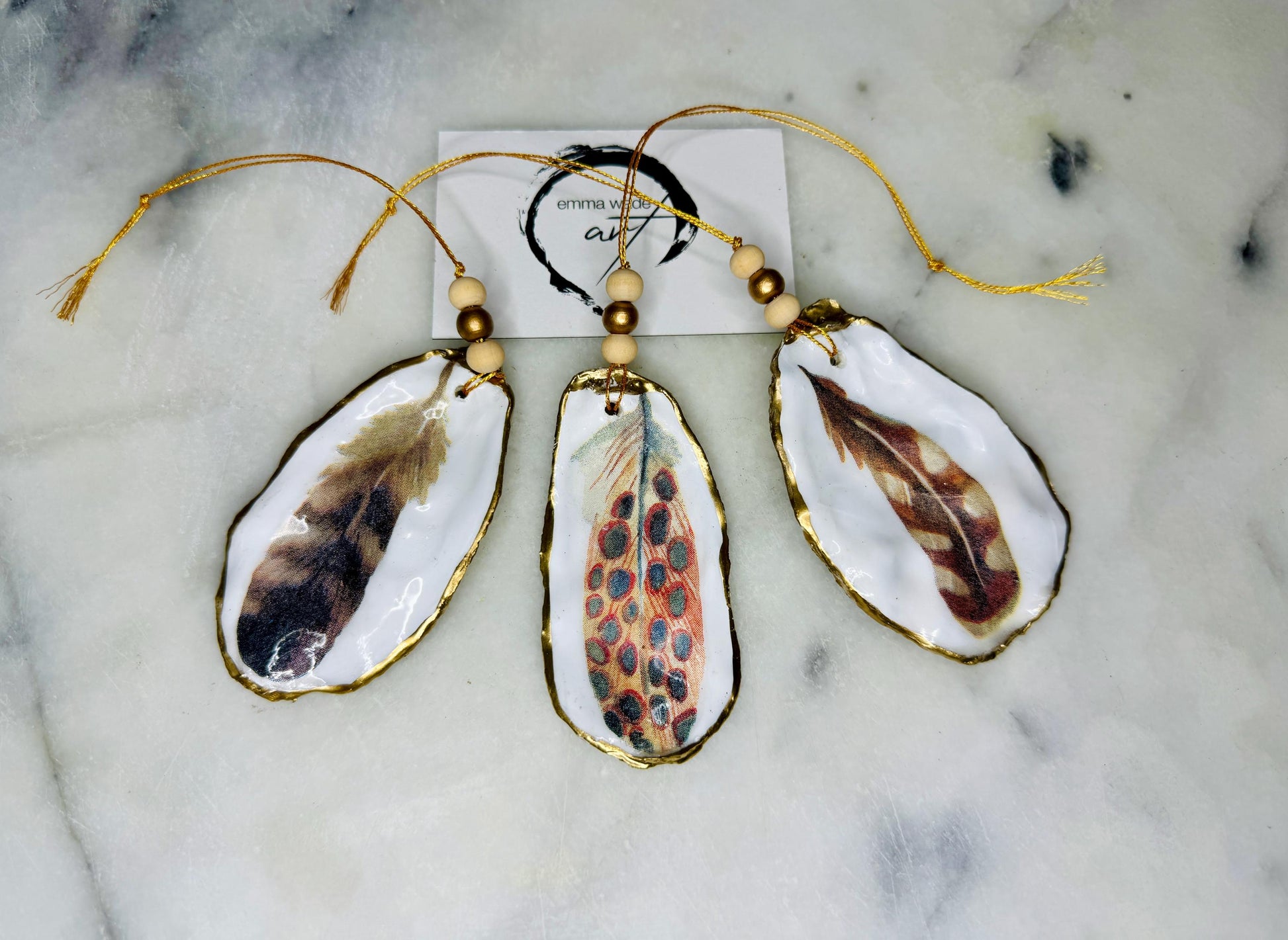 Aquarelle feather oyster shell hanging ornaments, handmade coastal décor, gilded gold leaf shells, resin sealed feather decorations, Christmas tree ornaments, nature-inspired gifts, watercolor feather oyster shells, Dorset handmade shell ornaments, sustainable coastal gifts, oyster shell art, feather design decorations, unique shell ornaments, eco-friendly handmade oyster shell Christmas gifts.