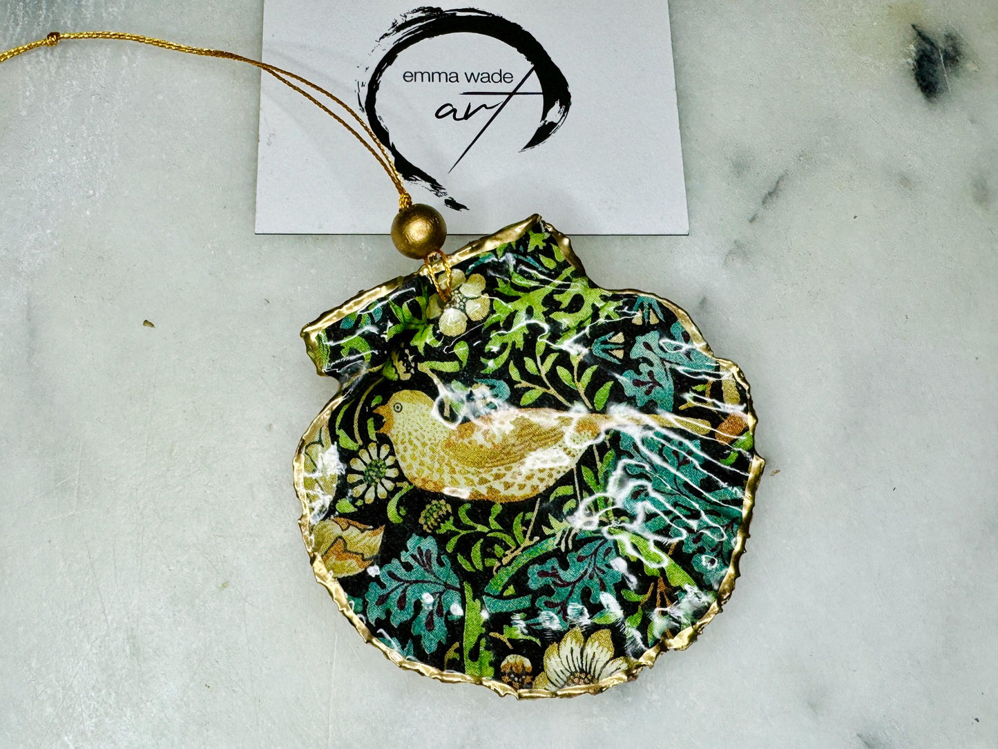 Handmade William Morris Strawberry Thief scallop shell hanging ornaments in four colourways with birds, floral patterns and gold leaf edging. Coastal shell ornaments finished in glossy resin with gold hanging cords for Christmas trees or year-round home decor. UK Heritage Gift