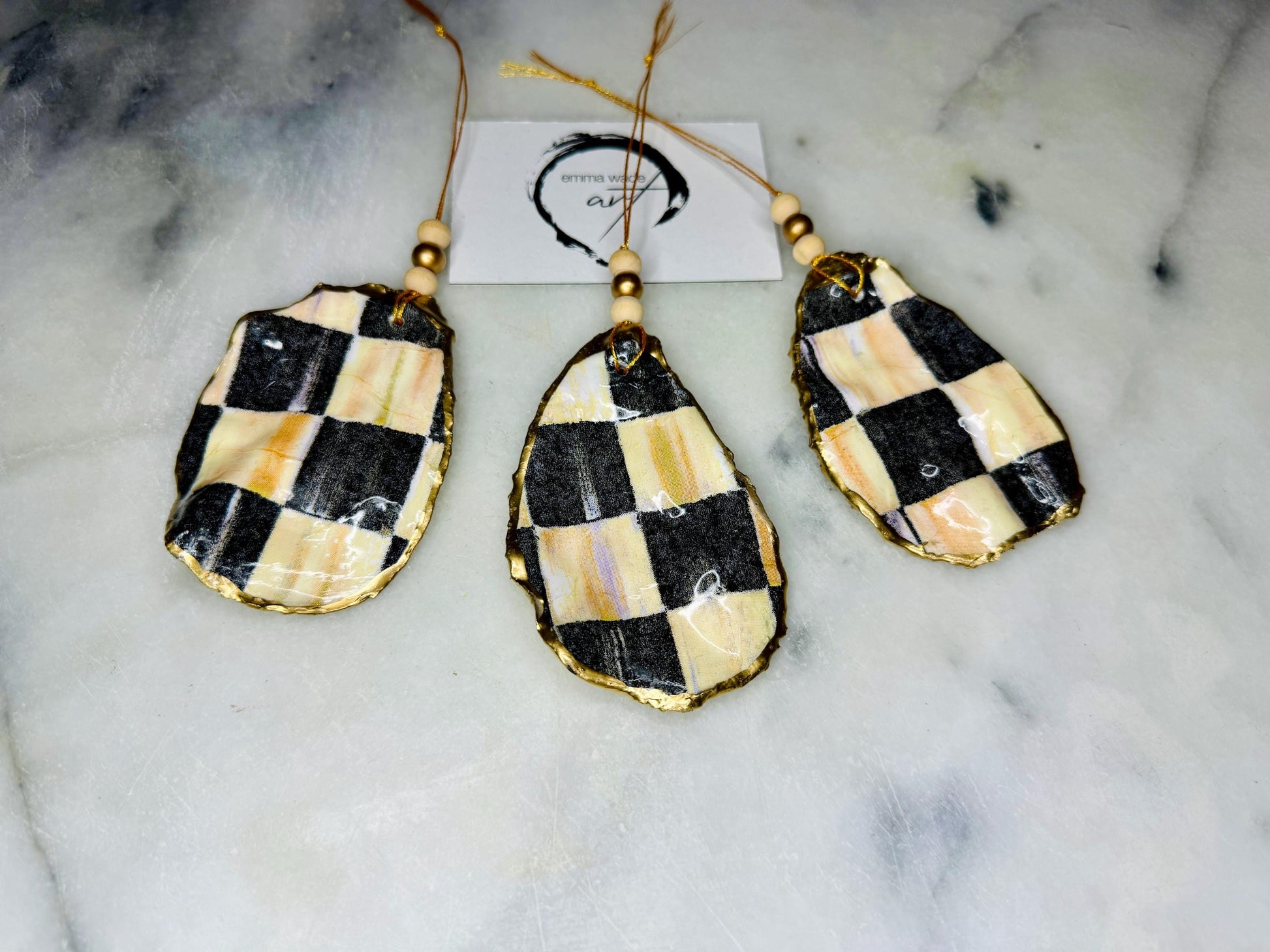 Black and Gold Oyster Shell Hanging Ornament, handmade from Dorset oysters, decoupaged and gilded with liquid gold leaf and sealed with gloss resin. Unique shell Christmas decoration, nautical ornament, chess chequer inspired design. Available individually or as a set of 3. Perfect eco friendly coastal gift, oyster shell bauble, luxury holiday decoration, ocean inspired home décor, handmade oyster art, and nature lover gift.