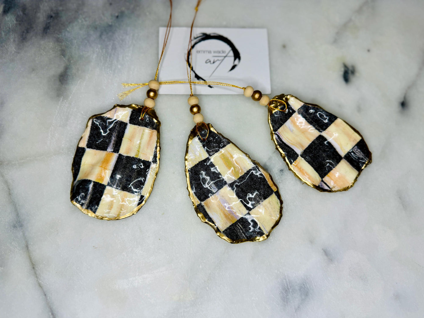 Black and Gold Oyster Shell Hanging Ornament, handmade from Dorset oysters, decoupaged and gilded with liquid gold leaf and sealed with gloss resin. Unique shell Christmas decoration, nautical ornament, chess chequer inspired design. Available individually or as a set of 3. Perfect eco friendly coastal gift, oyster shell bauble, luxury holiday decoration, ocean inspired home décor, handmade oyster art, and nature lover gift.