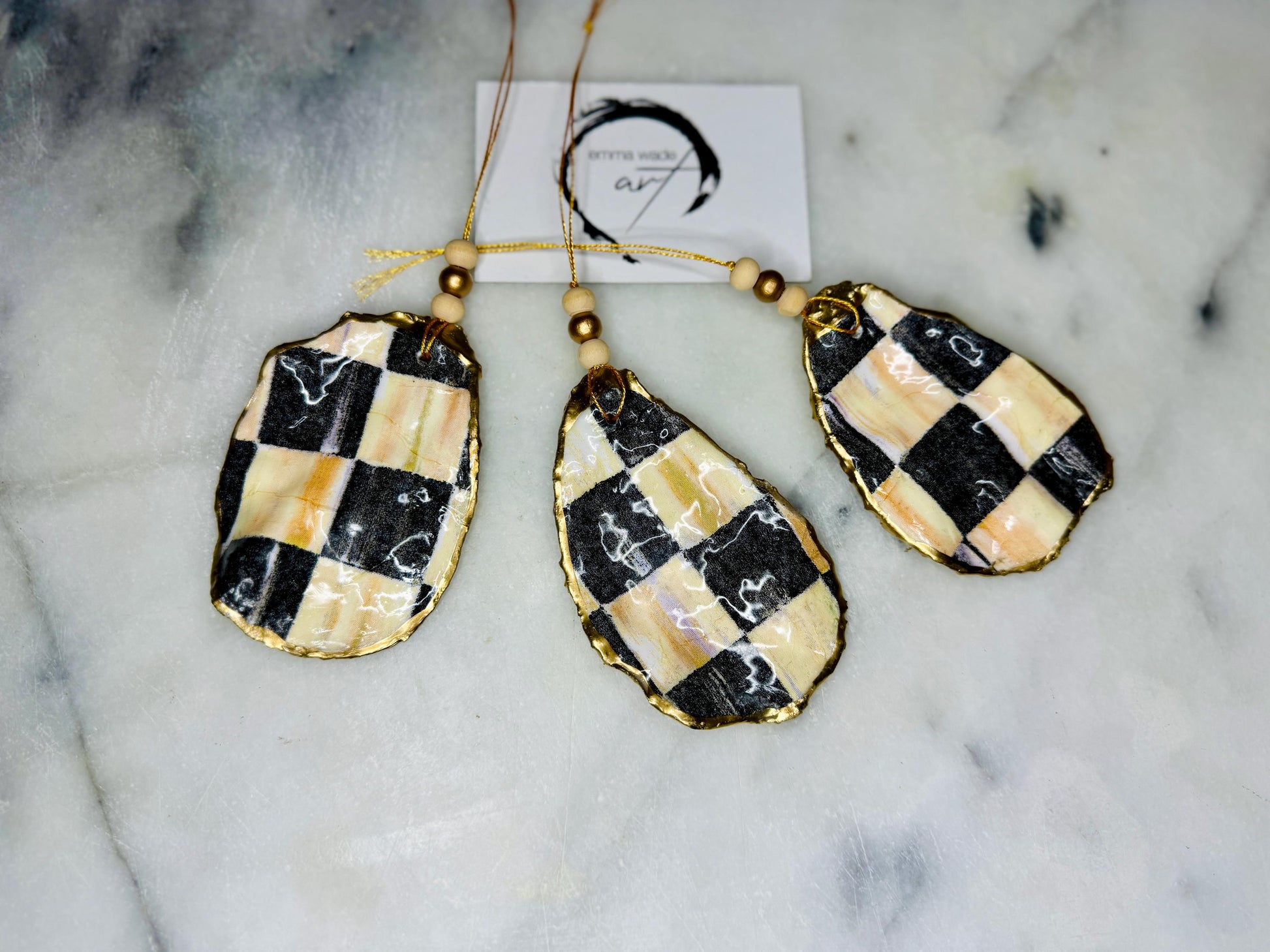 Black and Gold Oyster Shell Hanging Ornament, handmade from Dorset oysters, decoupaged and gilded with liquid gold leaf and sealed with gloss resin. Unique shell Christmas decoration, nautical ornament, chess chequer inspired design. Available individually or as a set of 3. Perfect eco friendly coastal gift, oyster shell bauble, luxury holiday decoration, ocean inspired home décor, handmade oyster art, and nature lover gift.