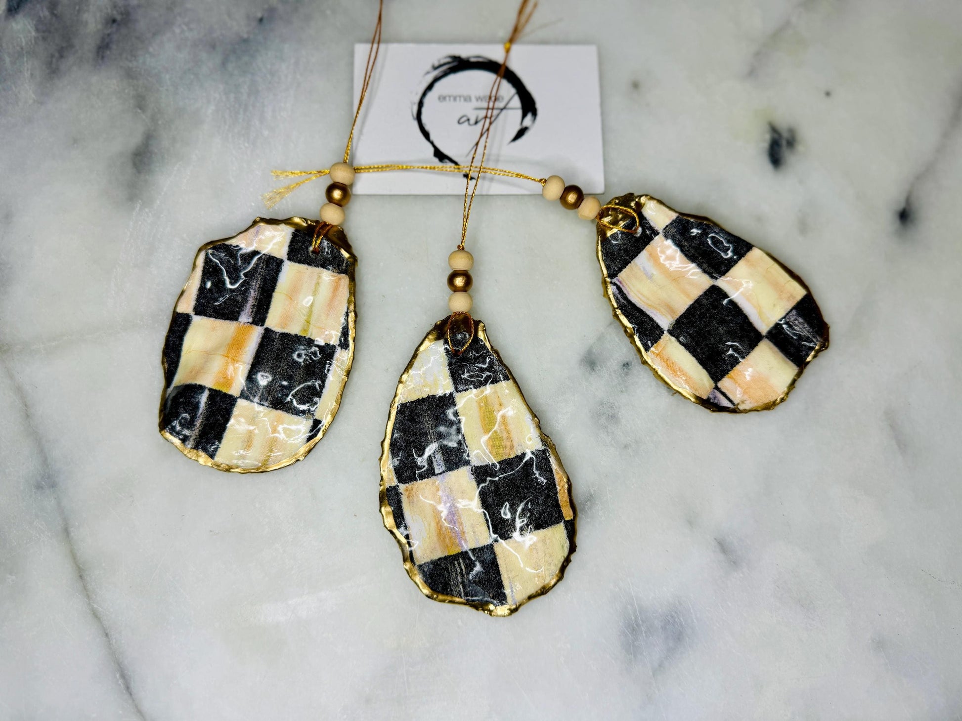 Black and Gold Oyster Shell Hanging Ornament, handmade from Dorset oysters, decoupaged and gilded with liquid gold leaf and sealed with gloss resin. Unique shell Christmas decoration, nautical ornament, chess chequer inspired design. Available individually or as a set of 3. Perfect eco friendly coastal gift, oyster shell bauble, luxury holiday decoration, ocean inspired home décor, handmade oyster art, and nature lover gift.