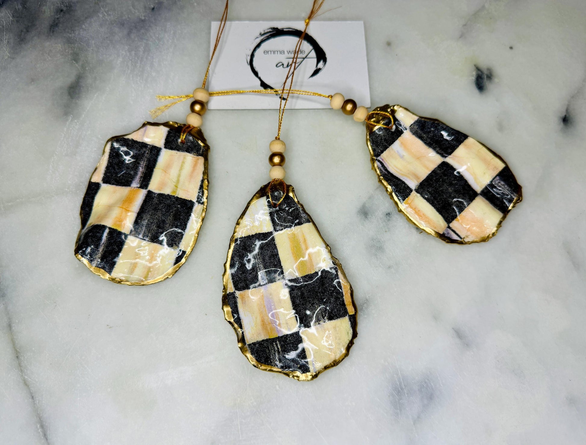 Black and Gold Oyster Shell Hanging Ornament, handmade from Dorset oysters, decoupaged and gilded with liquid gold leaf and sealed with gloss resin. Unique shell Christmas decoration, nautical ornament, chess chequer inspired design. Available individually or as a set of 3. Perfect eco friendly coastal gift, oyster shell bauble, luxury holiday decoration, ocean inspired home décor, handmade oyster art, and nature lover gift.