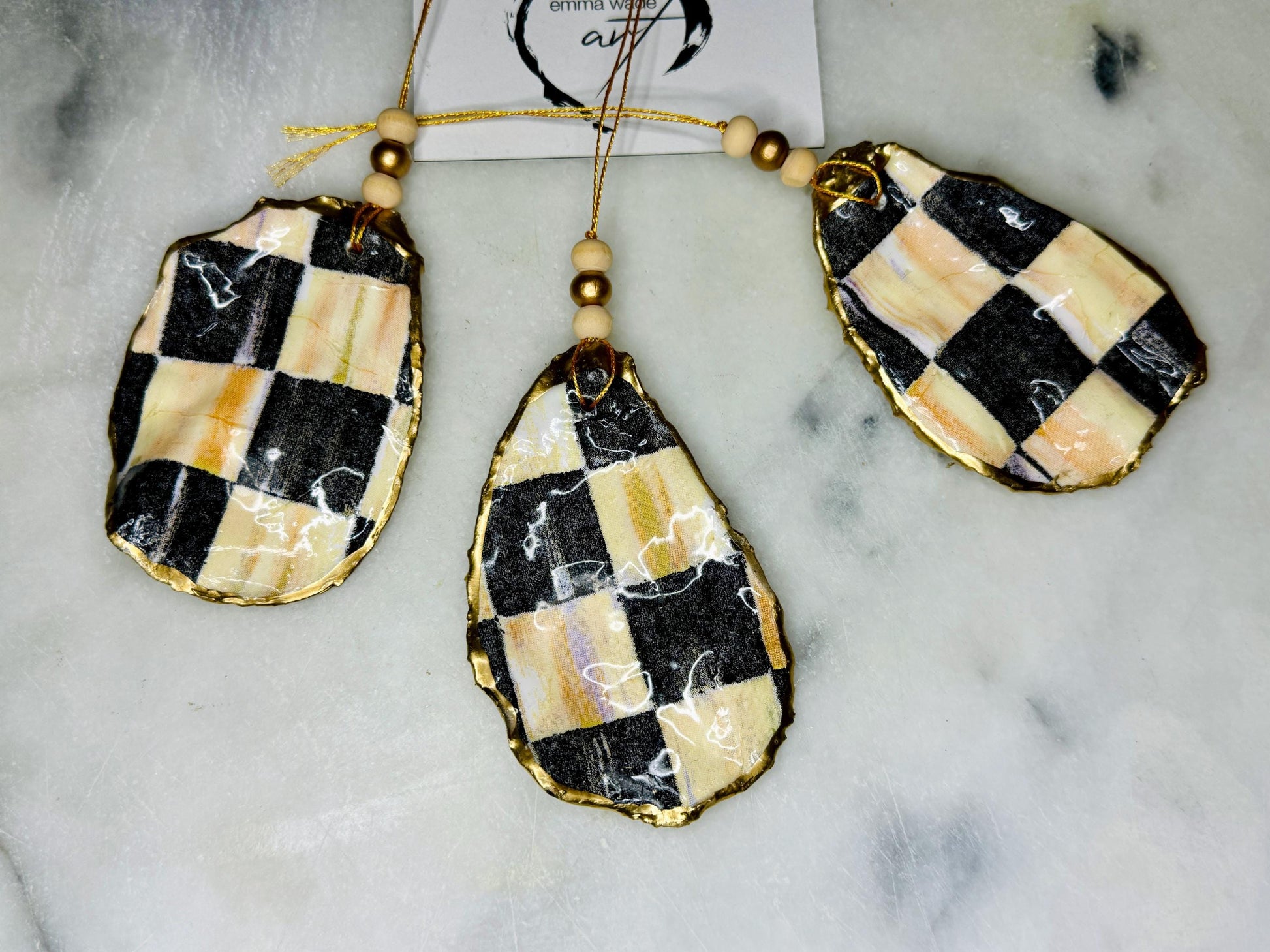 Black and Gold Oyster Shell Hanging Ornament, handmade from Dorset oysters, decoupaged and gilded with liquid gold leaf and sealed with gloss resin. Unique shell Christmas decoration, nautical ornament, chess chequer inspired design. Available individually or as a set of 3. Perfect eco friendly coastal gift, oyster shell bauble, luxury holiday decoration, ocean inspired home décor, handmade oyster art, and nature lover gift.
