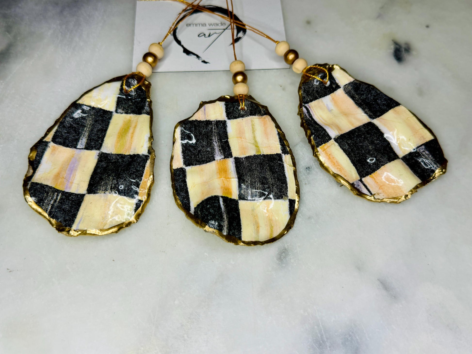 Black and Gold Oyster Shell Hanging Ornament, handmade from Dorset oysters, decoupaged and gilded with liquid gold leaf and sealed with gloss resin. Unique shell Christmas decoration, nautical ornament, chess chequer inspired design. Available individually or as a set of 3. Perfect eco friendly coastal gift, oyster shell bauble, luxury holiday decoration, ocean inspired home décor, handmade oyster art, and nature lover gift.