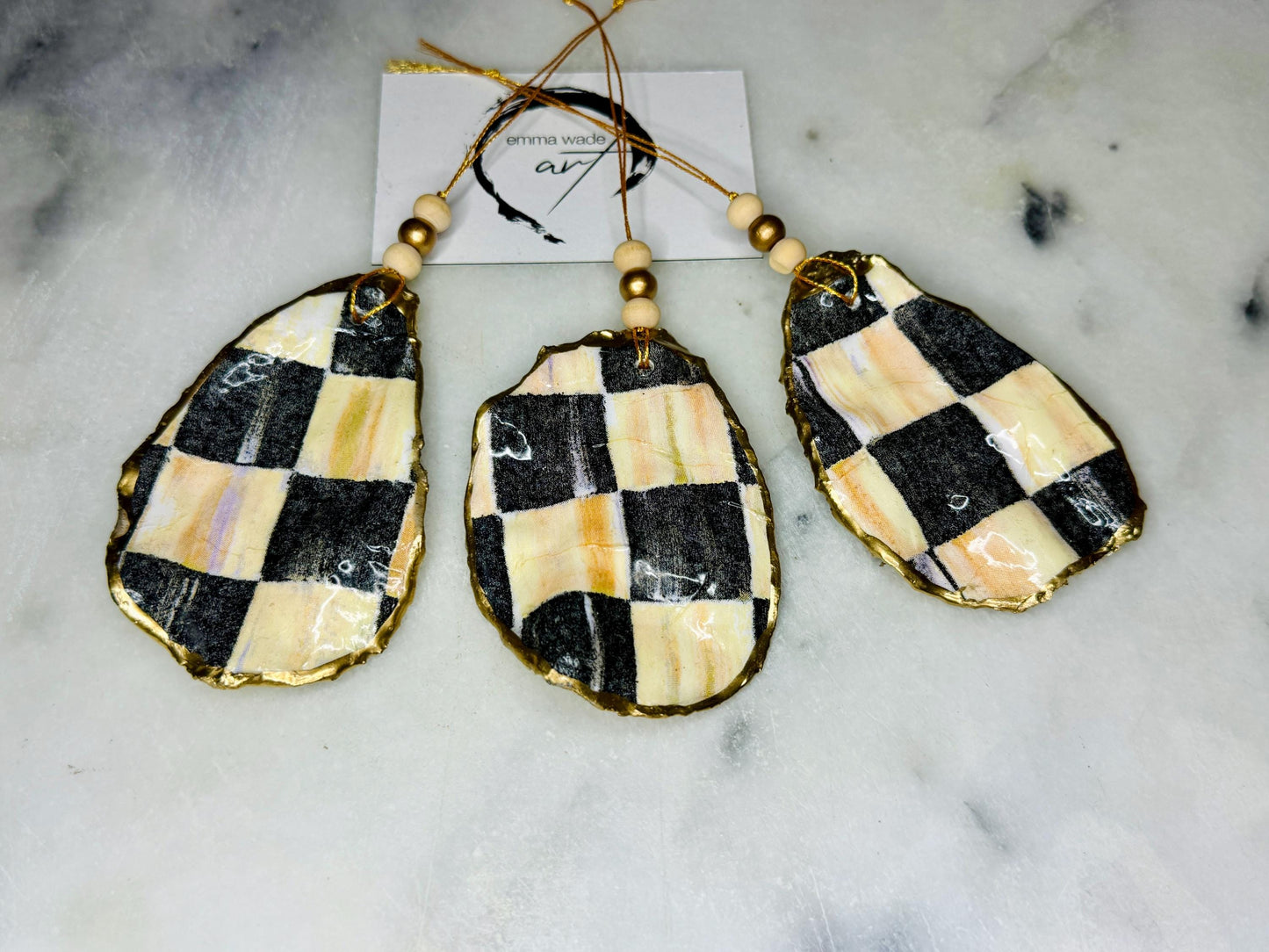 Black and Gold Oyster Shell Hanging Ornament, handmade from Dorset oysters, decoupaged and gilded with liquid gold leaf and sealed with gloss resin. Unique shell Christmas decoration, nautical ornament, chess chequer inspired design. Available individually or as a set of 3. Perfect eco friendly coastal gift, oyster shell bauble, luxury holiday decoration, ocean inspired home décor, handmade oyster art, and nature lover gift.
