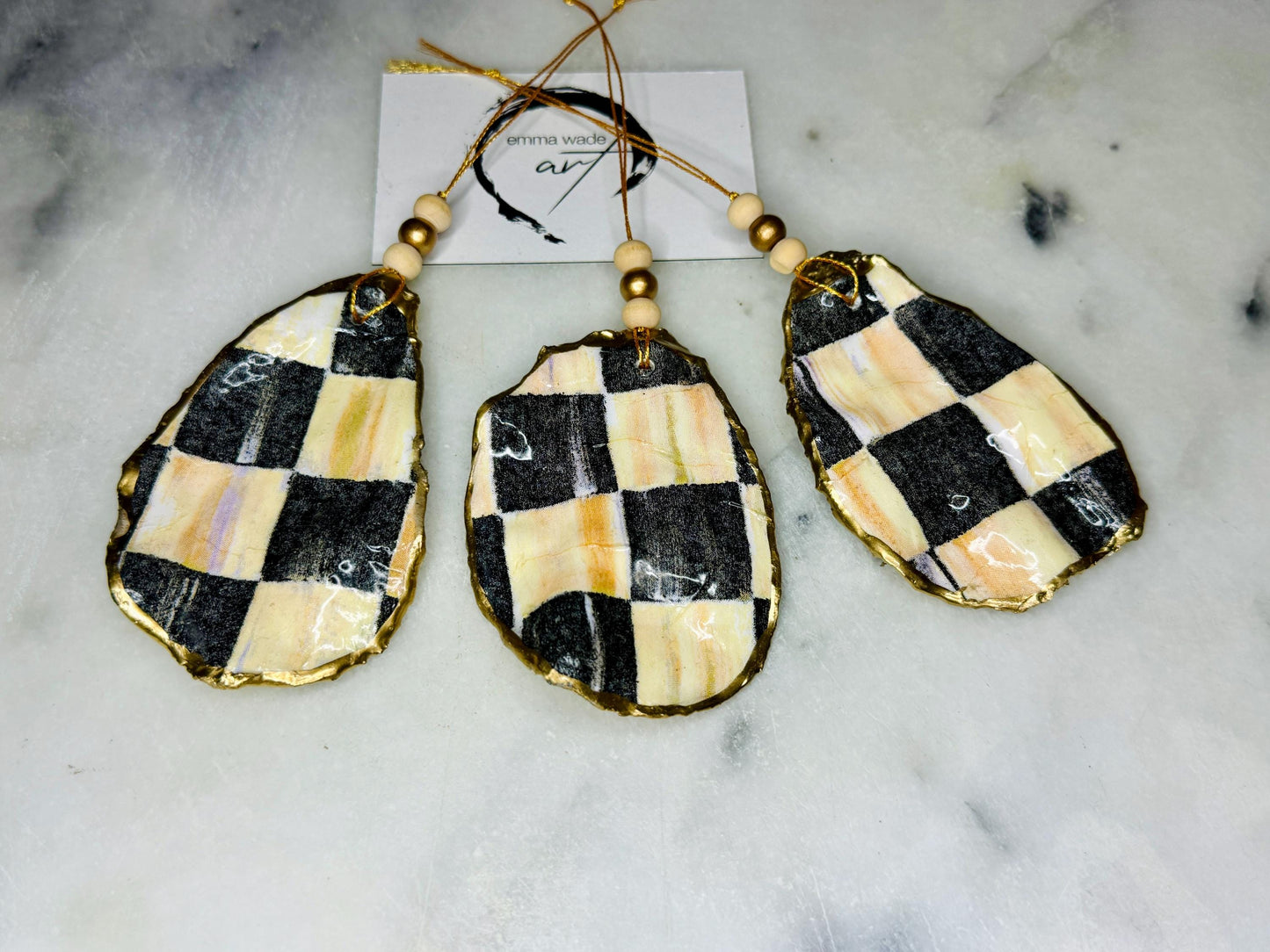 Black and Gold Oyster Shell Hanging Ornament, handmade from Dorset oysters, decoupaged and gilded with liquid gold leaf and sealed with gloss resin. Unique shell Christmas decoration, nautical ornament, chess chequer inspired design. Available individually or as a set of 3. Perfect eco friendly coastal gift, oyster shell bauble, luxury holiday decoration, ocean inspired home décor, handmade oyster art, and nature lover gift.