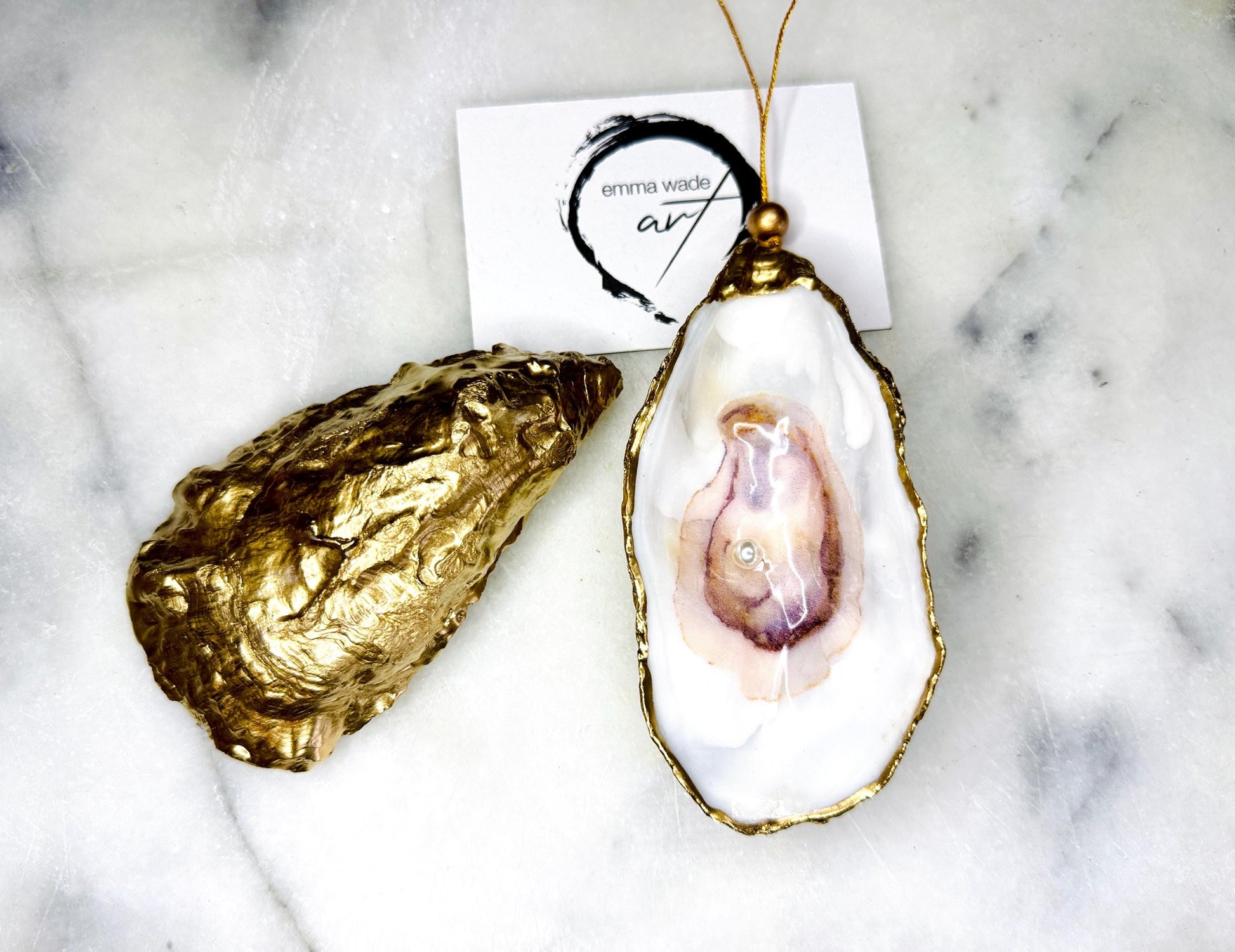 Handcrafted Dorset oyster shell hanging ornament decorated with a Swarovski pearl. Each natural oyster shell is finished with liquid gold leaf on the rim and back, sealed with crystal-clear glossy resin, and strung with gold cord and bead. Unique coastal Christmas decoration or tree bauble that can also be displayed year-round. A beautiful handmade oyster shell gift, ideal for weddings, anniversaries, Christmas stockings, bridesmaid keepsakes, or coastal-inspired home décor.