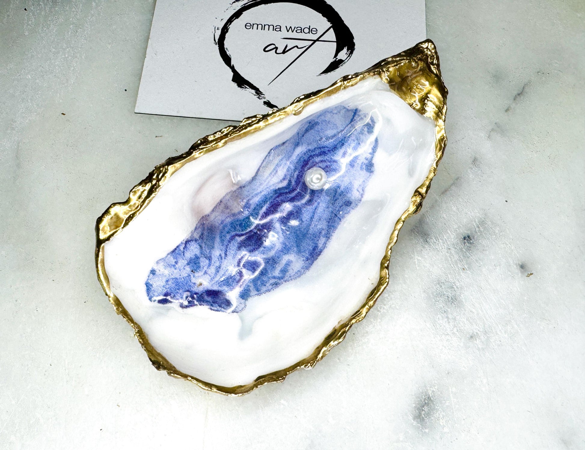 Handmade Dorset oyster shell jewellery dish with a natural pearl finish, gilded with liquid gold leaf and sealed in glossy resin. Each oyster shell features a Swarovski pearl inside, making it a unique ring holder, trinket tray, or coastal-inspired jewellery organiser. Perfect as a handmade oyster ring dish for weddings, anniversaries, birthdays, or as a bridesmaid gift. A one-of-a-kind shell catchall tray, ideal for coastal home décor or thoughtful handmade presents.