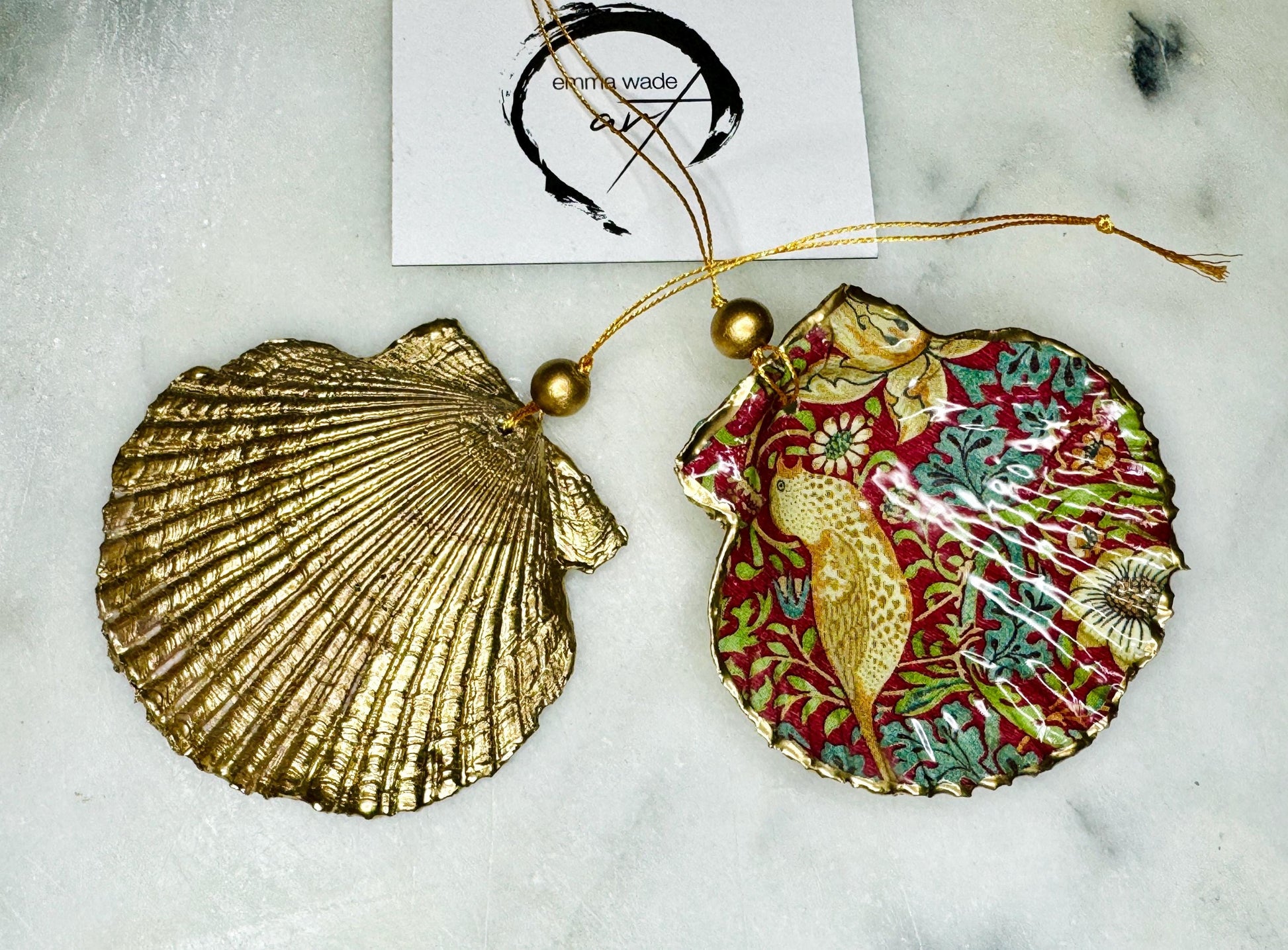 Handmade William Morris Strawberry Thief scallop shell hanging ornaments in four colourways with birds, floral patterns and gold leaf edging. Coastal shell ornaments finished in glossy resin with gold hanging cords for Christmas trees or year-round home decor. UK Heritage Gift