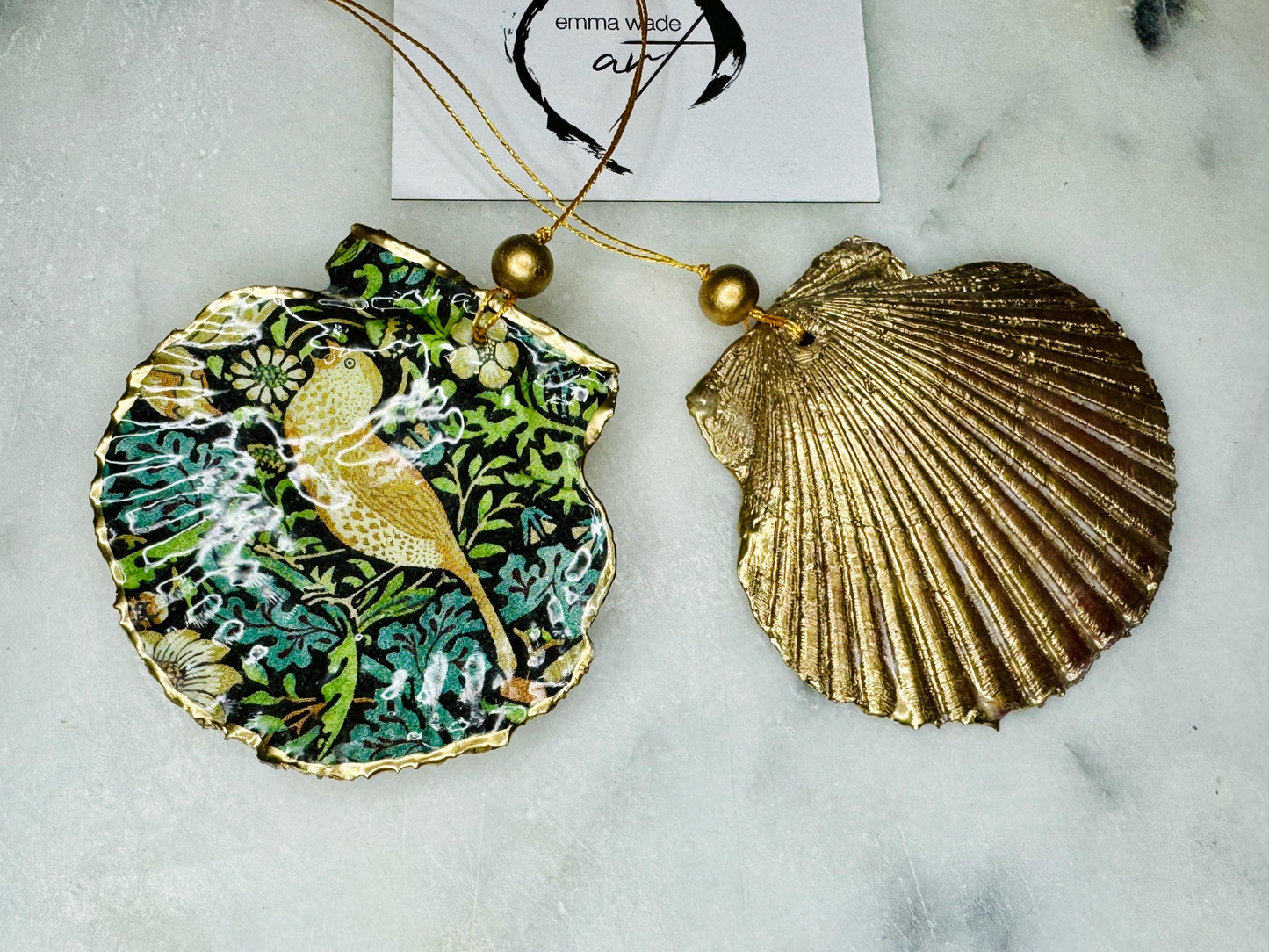 Handmade William Morris Strawberry Thief scallop shell hanging ornaments in four colourways with birds, floral patterns and gold leaf edging. Coastal shell ornaments finished in glossy resin with gold hanging cords for Christmas trees or year-round home decor. UK Heritage Gift