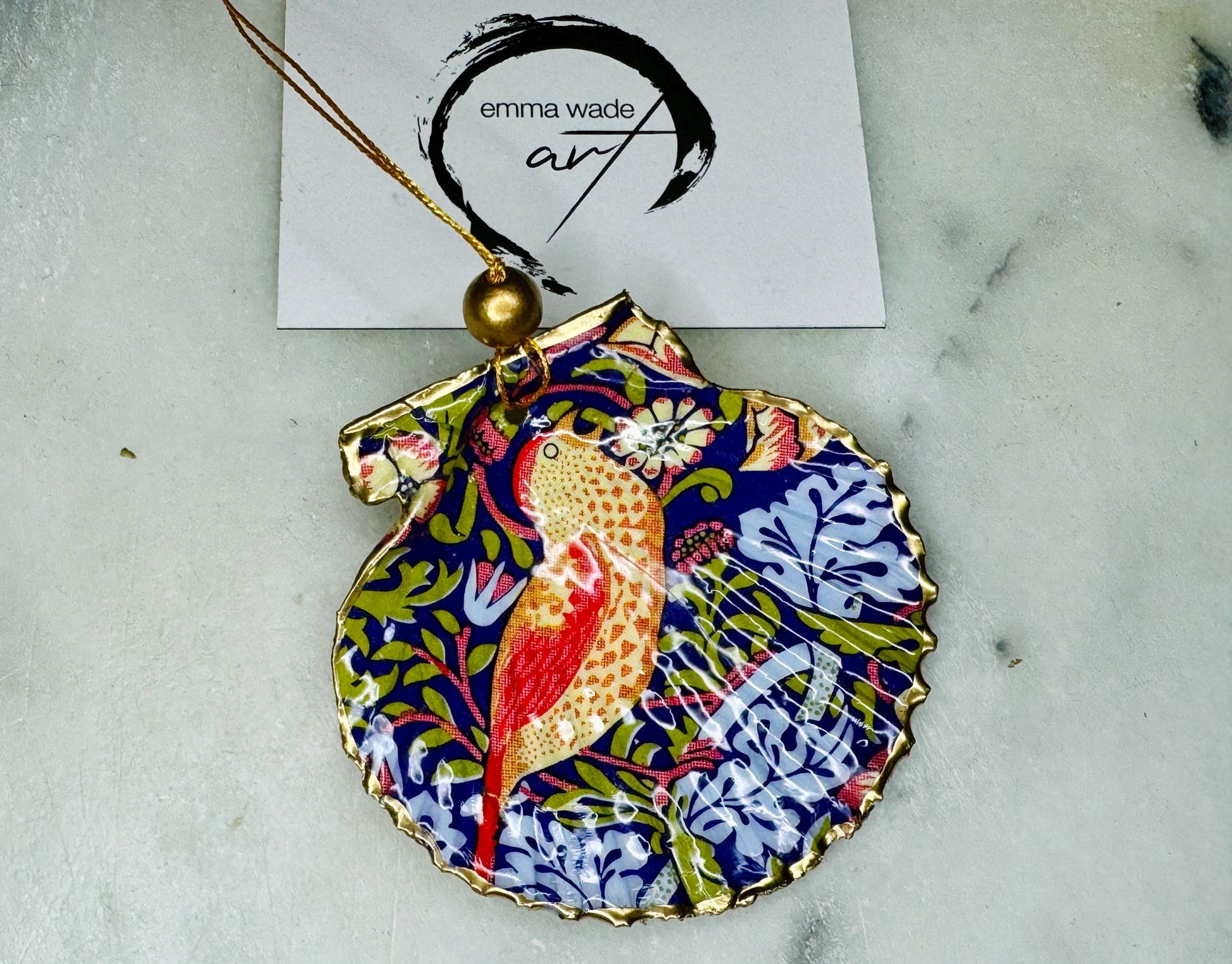 Handmade William Morris Strawberry Thief scallop shell hanging ornaments in four colourways with birds, floral patterns and gold leaf edging. Coastal shell ornaments finished in glossy resin with gold hanging cords for Christmas trees or year-round home decor. UK Heritage Gift